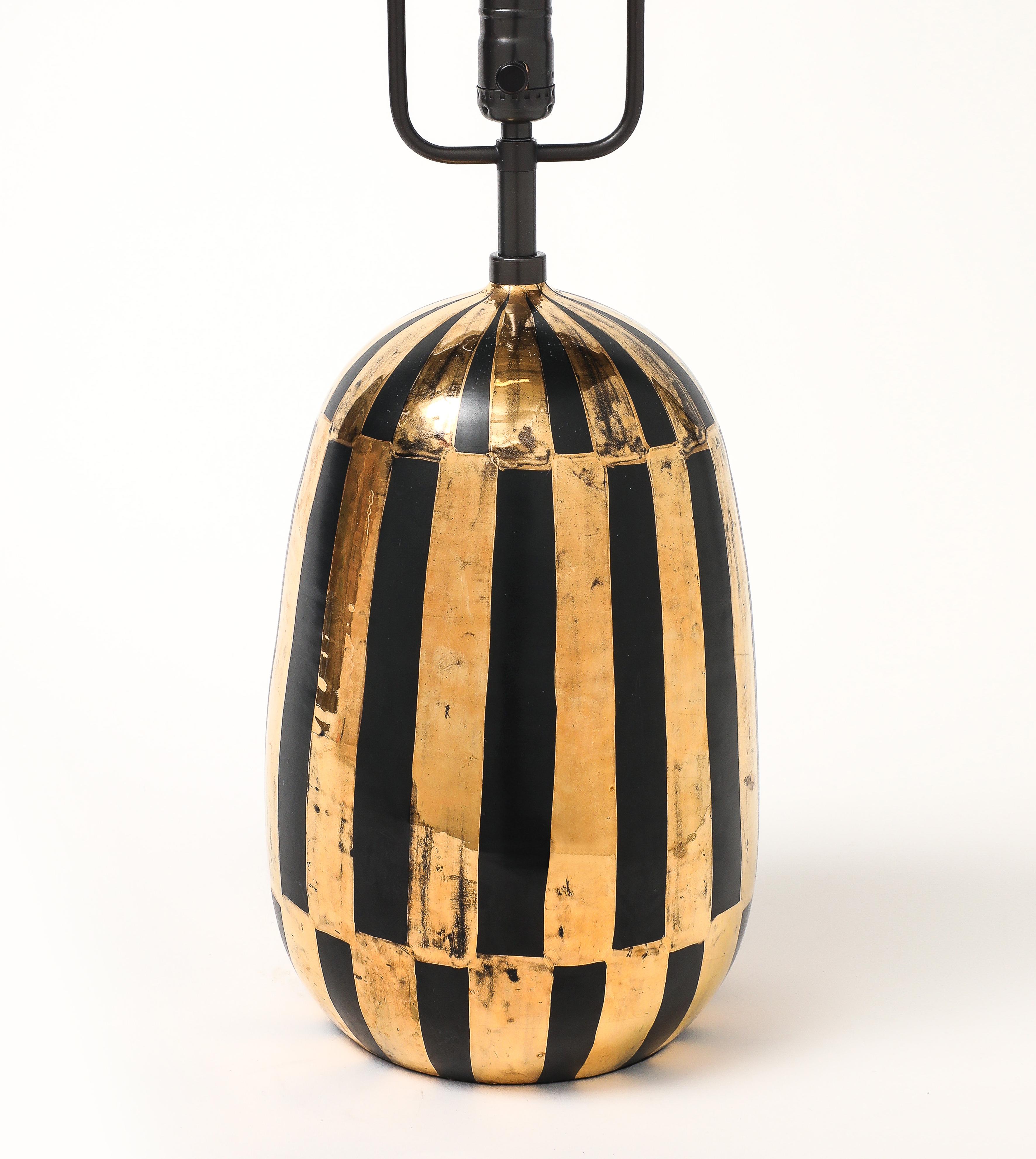 Lampe Bitossi, céramique, rayures or et noires, signée. Lampe de table de forme ovoïde de taille moyenne, émaillée de bandes verticales noires audacieuses sur un corps en terre cuite émaillé d'or métallique. Le corps en céramique mesure 14,19 pouces