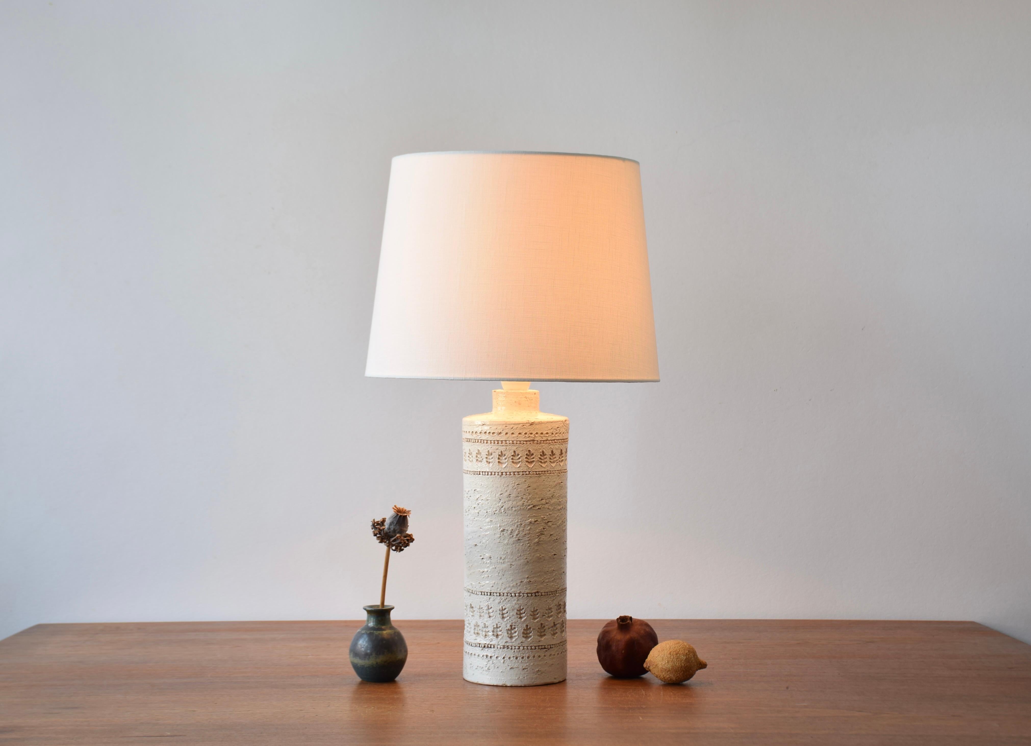 Lampada da tavolo alta e vintage in ceramica Bitossi con smalto bianco.
La lampada ha un decoro a foglie stilizzate impresso. 
Il disegno è attribuito ad Aldo Londi.

La lampada è stata prodotta tra gli anni '60 e '70 circa.

È incluso un nuovo