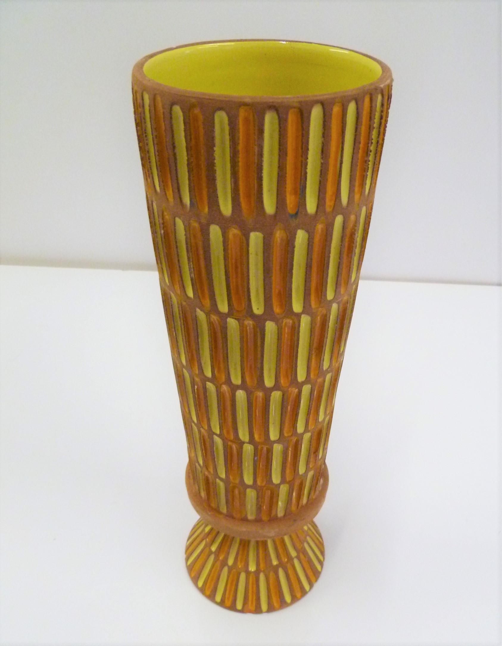 A tall Italian Mid-Century Modern footed Pottery vase produced by Bitossi in the 1960s for retailer Raymor and designed by Aldo Londi. This vase features an unglazed clay body with glazed incisions colored in bright orange and lemon yellow and lemon
