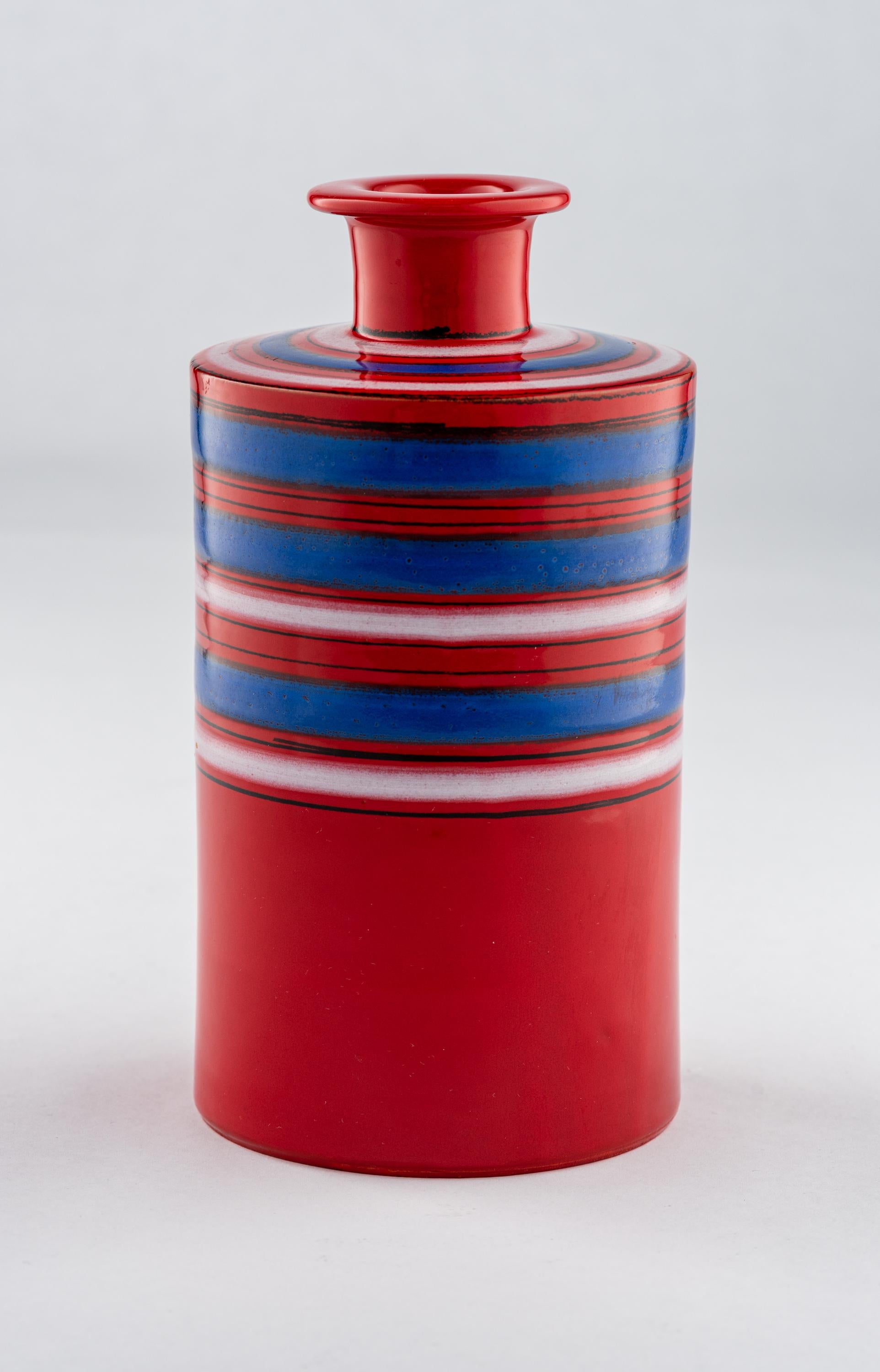 Vase Bitossi Raymor, céramique, rayures, rouge, bleu, blanc, signé. Vase cylindrique de petite taille, de forme moderniste, décoré de rayures rouges, bleues et blanches. Signé avec l'étiquette Raymor qui se lit : 555 BIT. Conserve l'étiquette