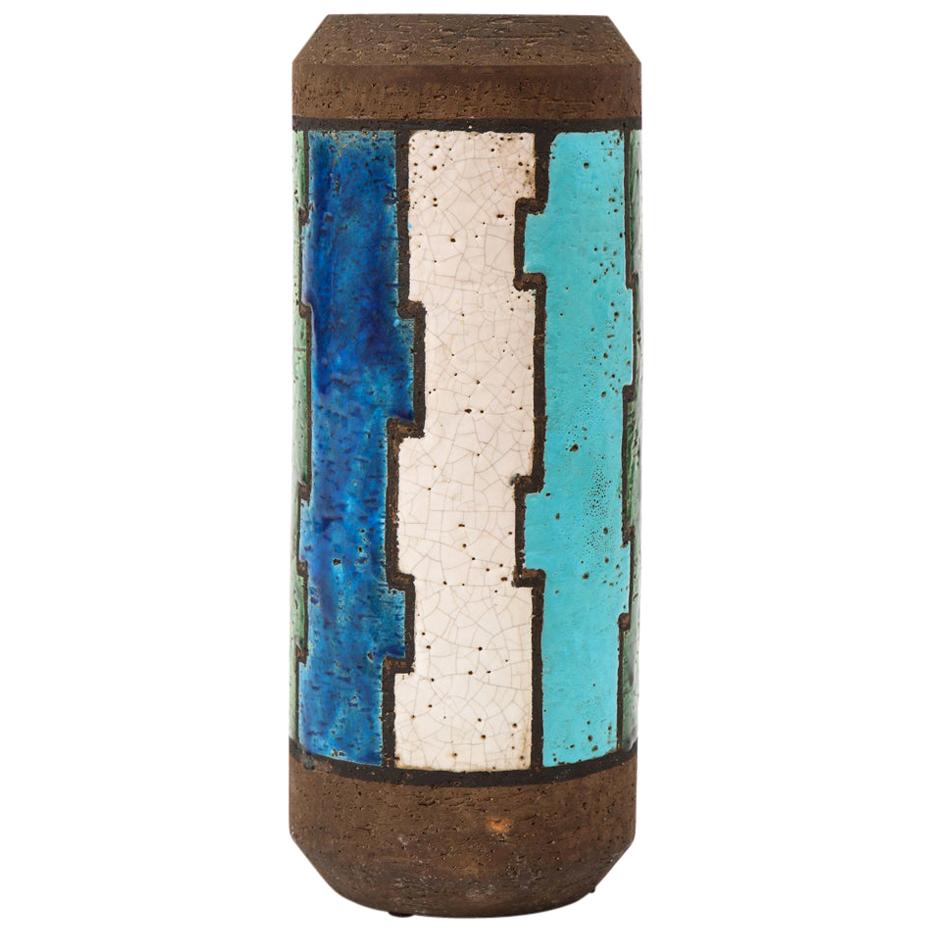 Bitossi vase, ceramic, blue, white, green and brown, geometric, signed. Tall chunky cylinder vase decorated with a puzzle pieces pattern and glazed in sky and navy blue, green and white over a coarse matte brown clay body. Named Líneas Rotas (Broken