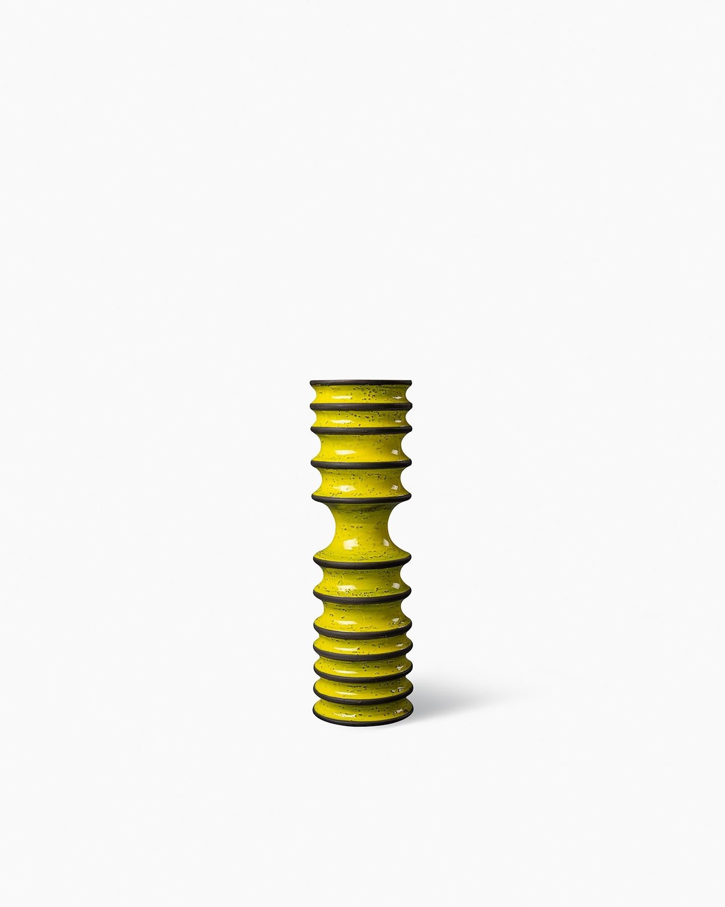 La colección presenta una secuencia de formas en espiral que evolucionan hacia varias dimensiones, presentadas en colores cálidos como el amarillo y el naranja, intercalados con finas bandas marrones que acentúan los contornos. Realizadas mediante