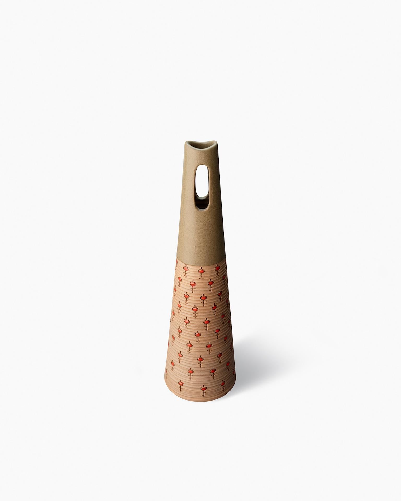 Forma cónica hecha al torno en arcilla roja con cortes ovalados en la parte superior. Decorado con un pequeño motivo de llave incisa con un sello. Esmalte verde oliva mate con pinceladas de esmalte rojo brillante dentro de las incisiones.

Año de