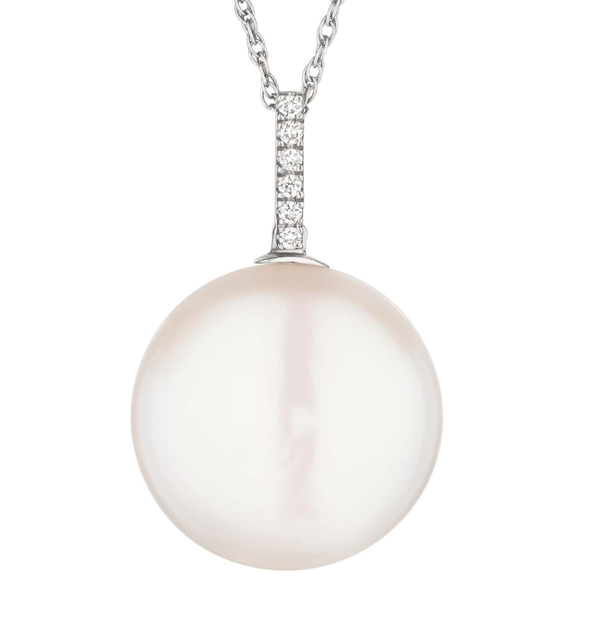 Embrace minimalist elegance with this pearl pendant, featuring a 9 mm. round flat freshwater coin pearl nestled in a sleek 18k white gold bezel. A trail of sparkling 0.05 ct. diamonds ascends to the delicate chain, adding just the right touch of