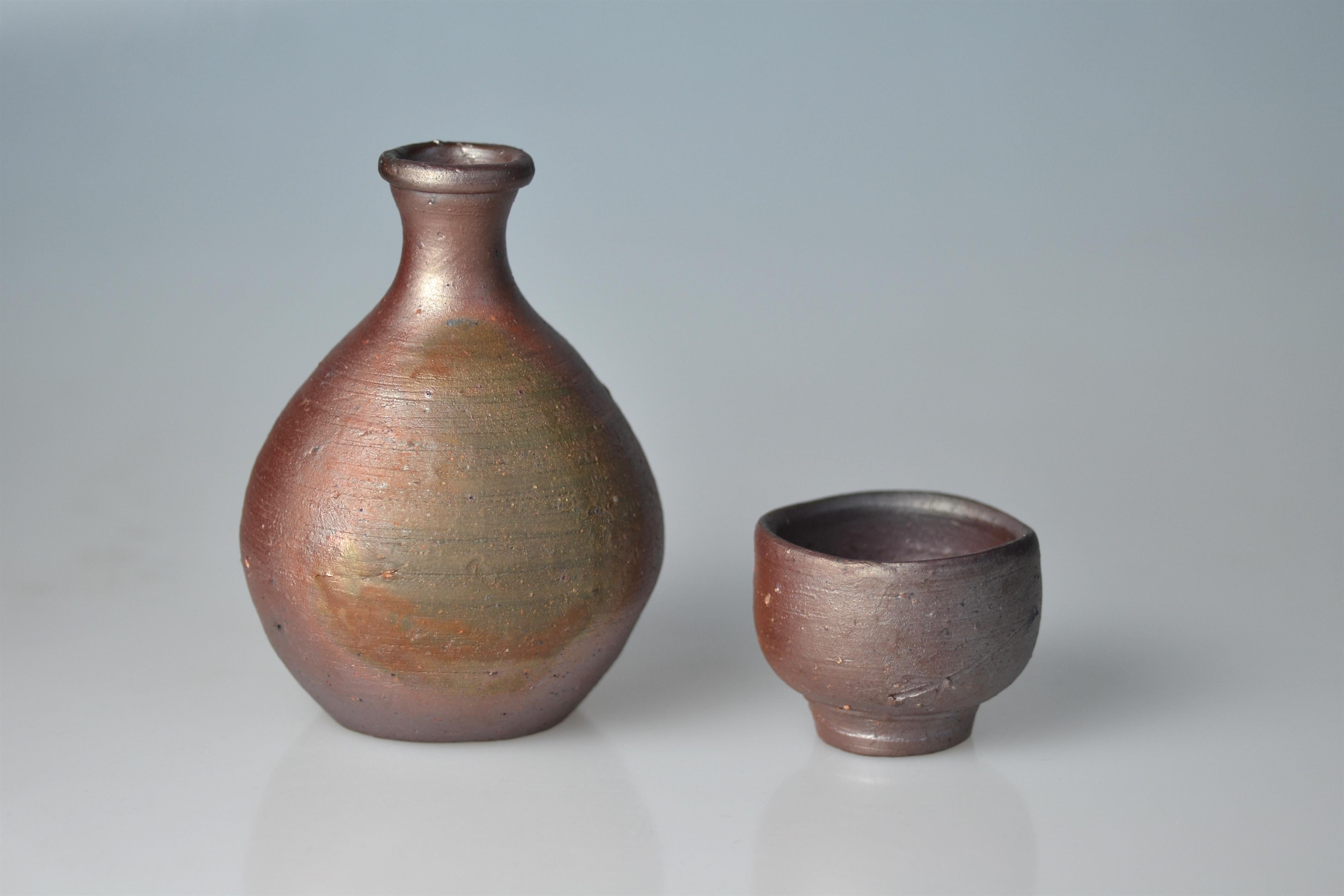 This set of a Bizen sake flask and cup was made by Fujiwara Yu who was born 1932 in Honami in Bizen, Okayama prefecture. As son of famous Fujiwara Kei (1899-1983) he has also been awarded the title 