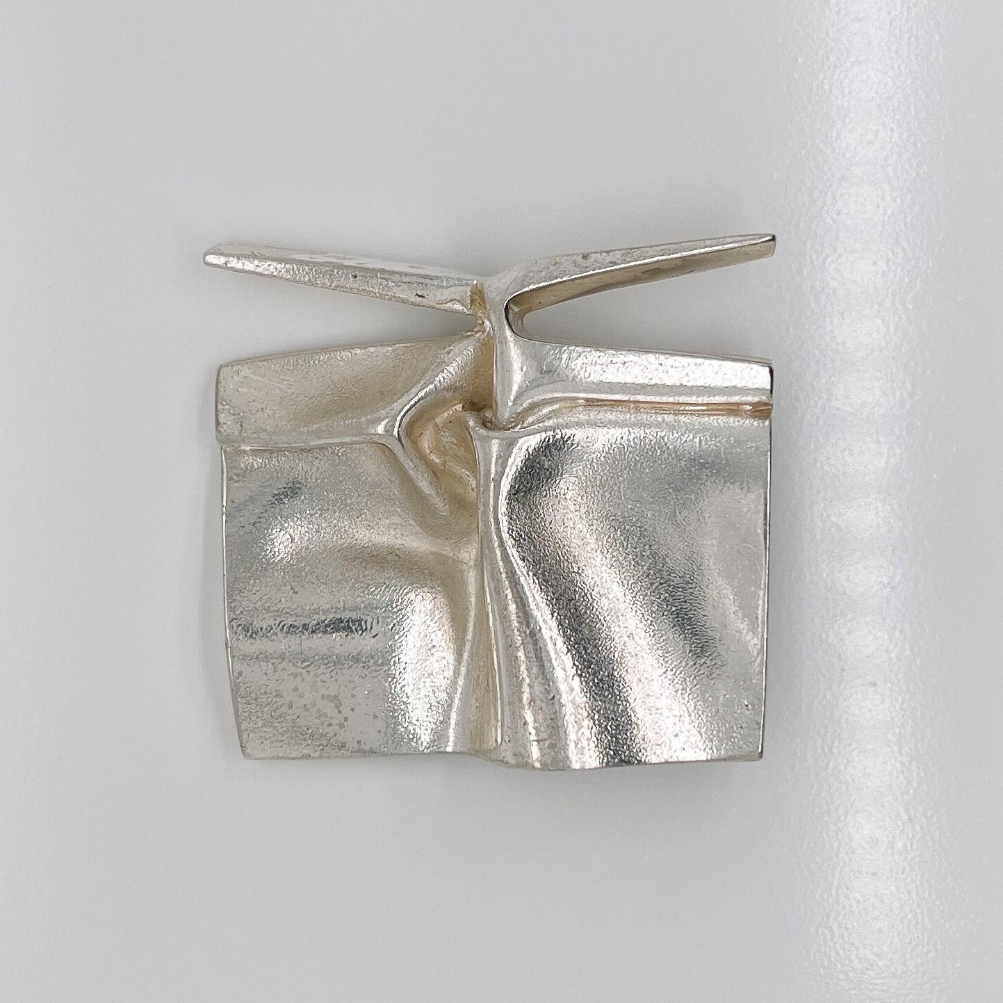 A very fine Finnish modernist sterling silver brooch or pendant. 

By Björn Weckstrom for Lapponia.

Fashioned in cast silver to look and feel like folded metal or fabric.

Worn as a brooch or pin (and also with two integral bails on the reverse to