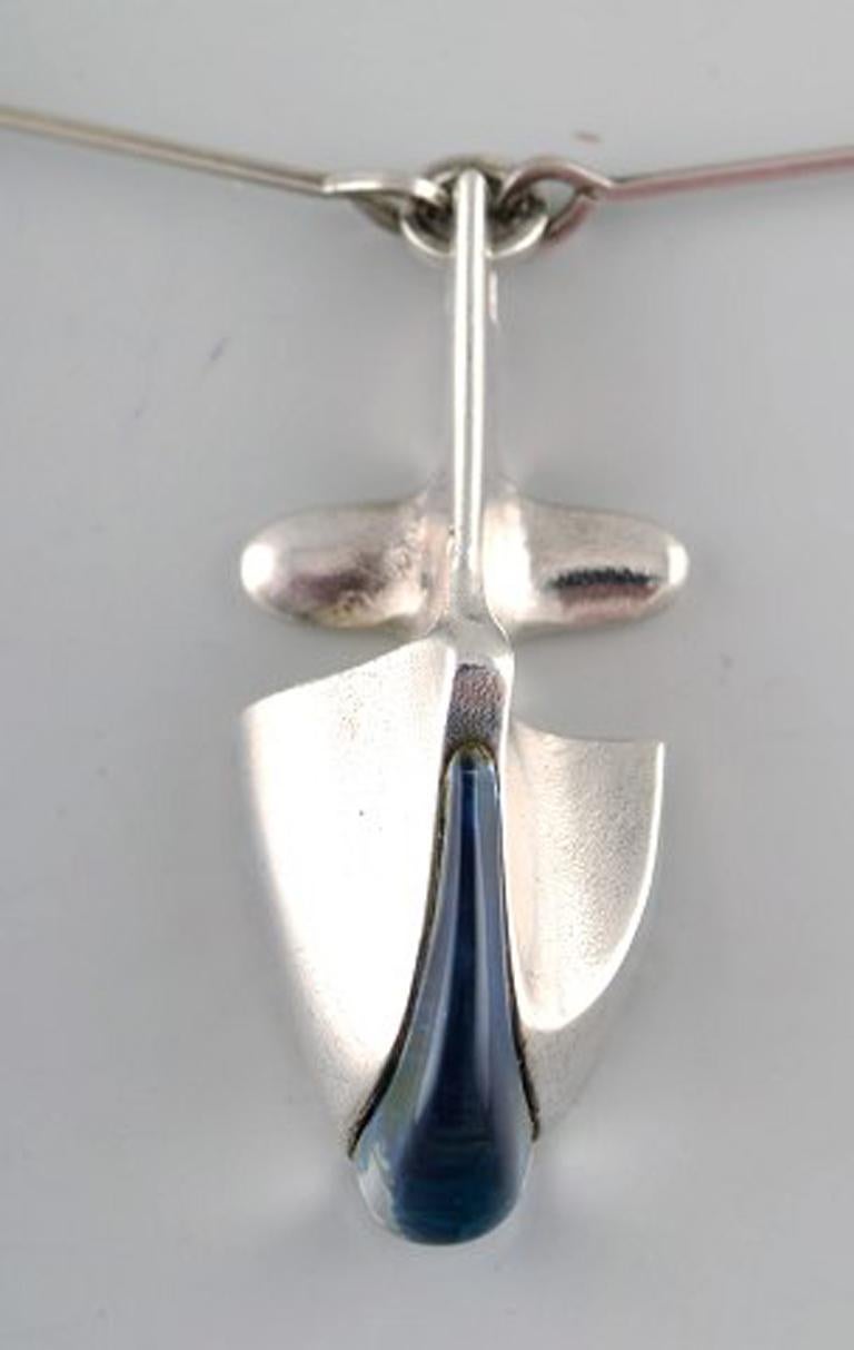 Björn Weckström, Lapponia, Finland.
Vintage modernist necklace in sterling silver with blue stone in pendant, handmade.
1960 s.
Stamped.
Chain measures 43 cm. Pendant measures 2,6 cm x 2,7 cm.