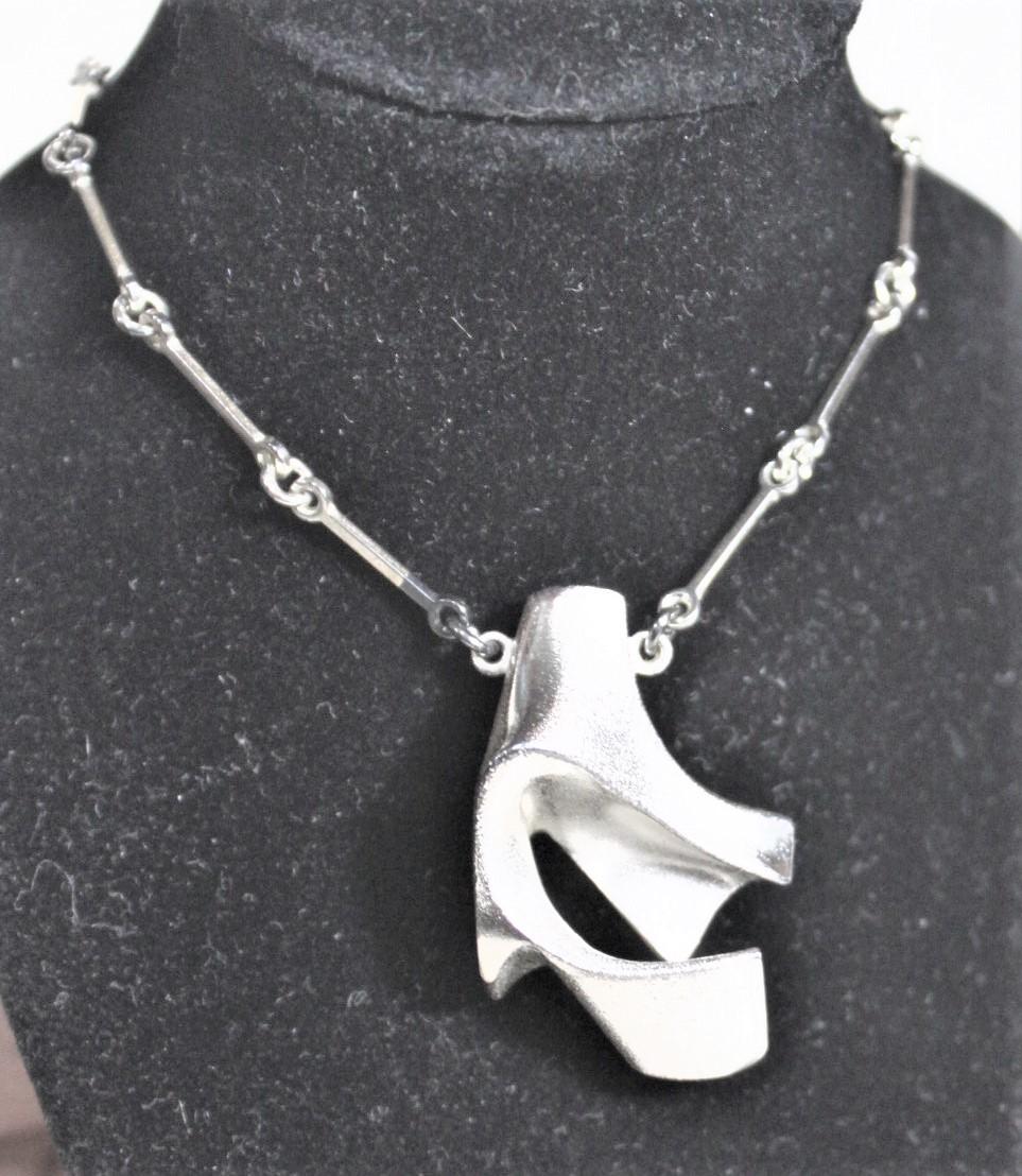 This sterling silver and acrylic pendent and chain were done by the renowned Finnish jewelry maker, Bjorn Weckstrom in his signature Organic Modernist style in approximately 1970. This pendent is done in a biomorphic shape of sterling silver and