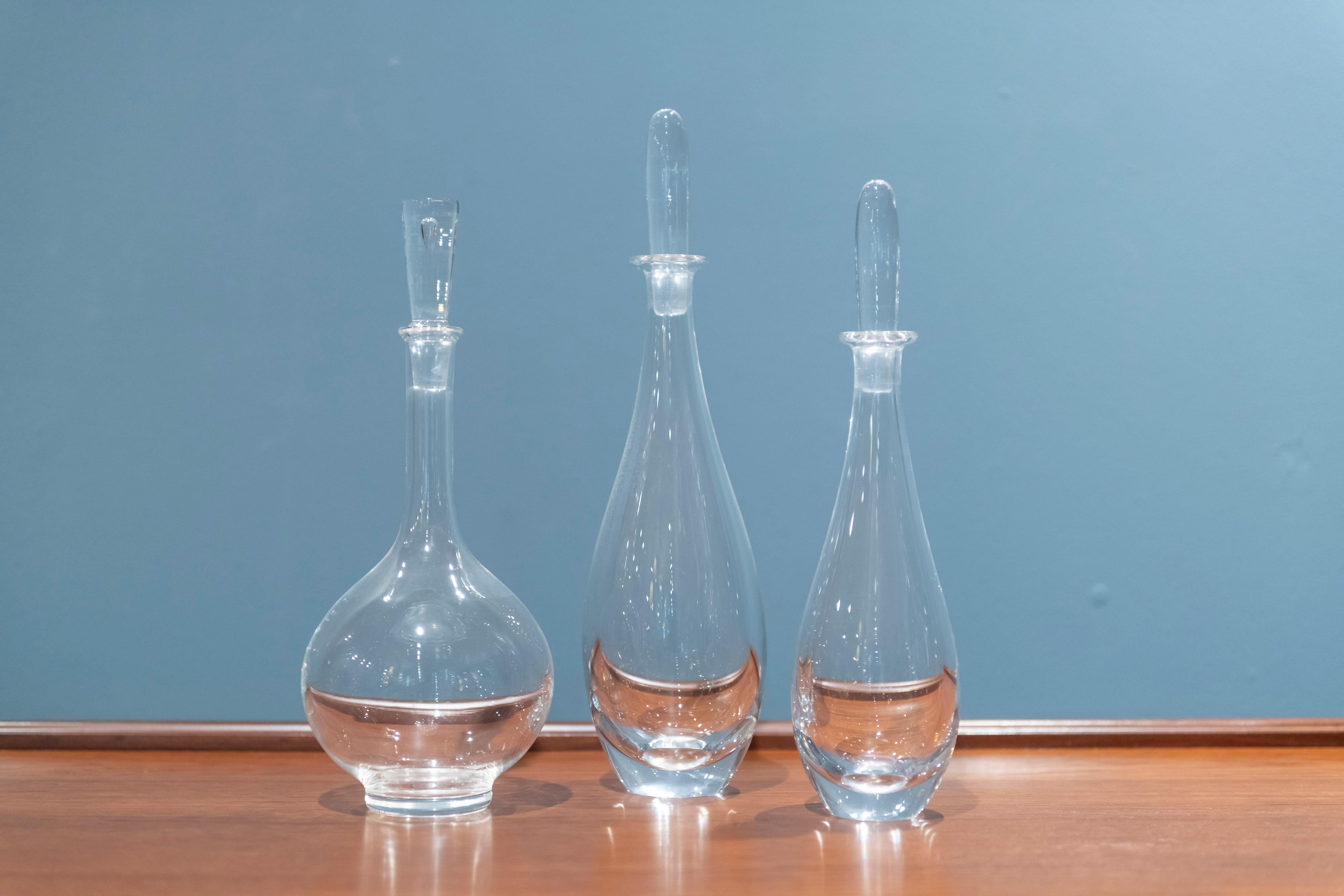 Pair of Orrefors decanters designed by Bjorn Wiinblad and a single Steuben glass decanter, all signed.