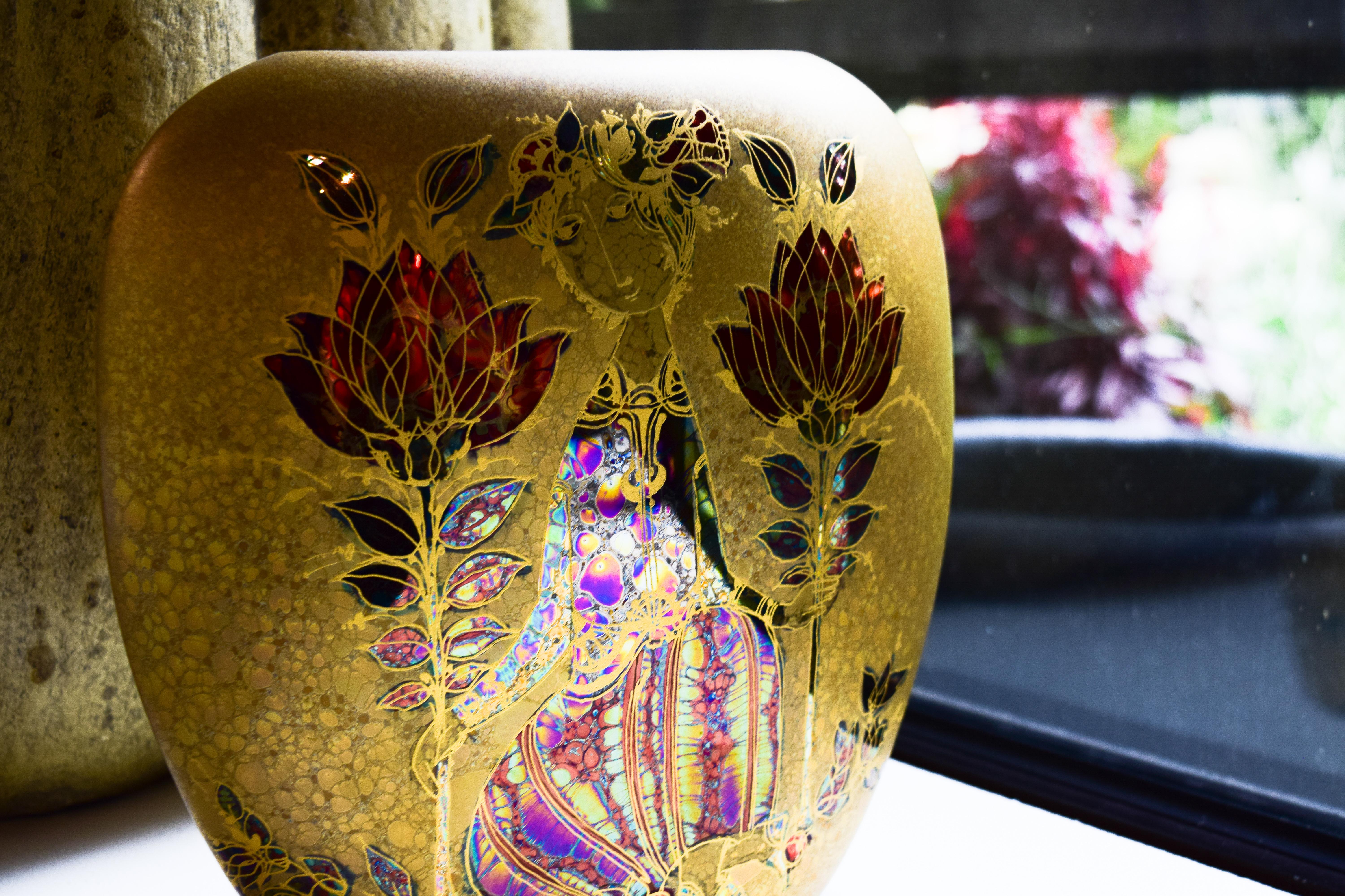 This vase is one example of the captivating style brought to life by the whimsical mind of artist Bjorn Wiinblad. Delightfully colored in metallics and 24-karat gold, the vase features the trademark round faces and complex detail that made Wiinblad