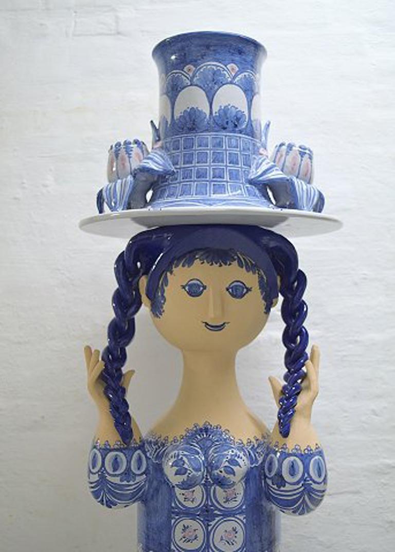 Bjorn Wiinblad: Very rare and monumental female figure of stoneware, in five parts, top with flower pot in the shape of a hat.
Decorated with blue-colored motifs on light gray base, braids with dark blue glaze.
Measures: Height incl. base 158 cm.,