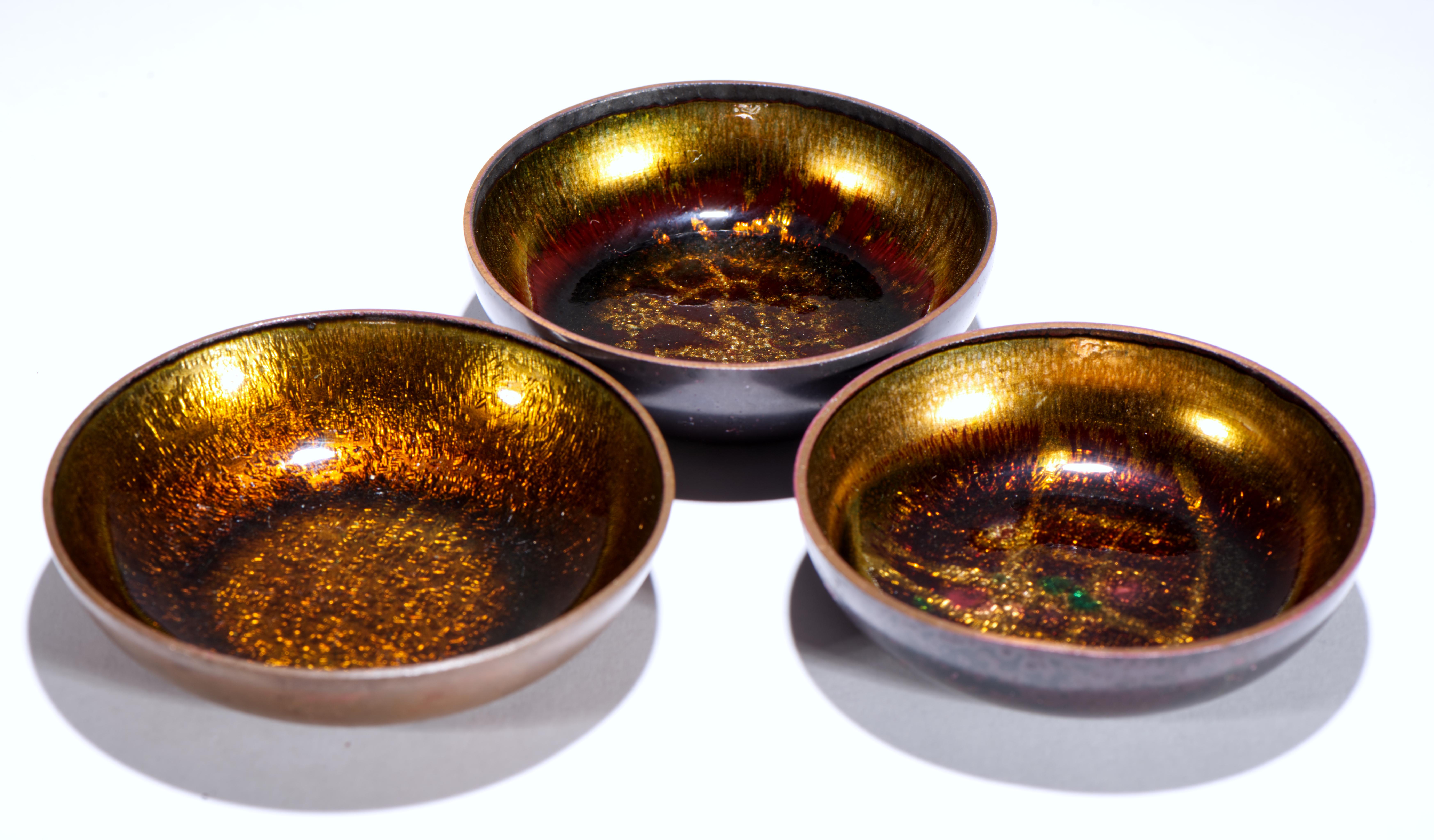 Vintage set of 2 smaller bowls and one larger bowl feature minimal Mid Century Modern forms and striking Scandinavian Modern enamel decor in organic brown colors with jewel tone accents. The smaller bowls feature abstract geometric designs in