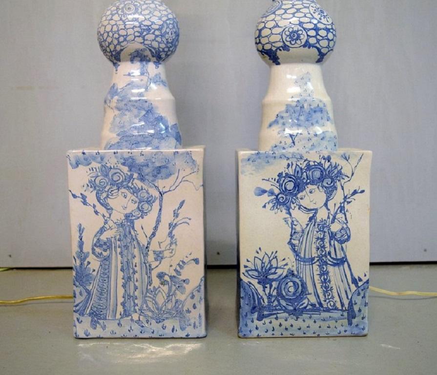 Bjørn Wiinblad (1918-2006), Dänemark. 
Zwei kolossale, einzigartige Stehlampen aus blau glasierter Keramik, verziert mit jungen Frauen, umgeben von Blumenornamenten. 
Original gelbe Bildschirme. Datiert 1978.
Maße: 105 x 42 cm (inkl.