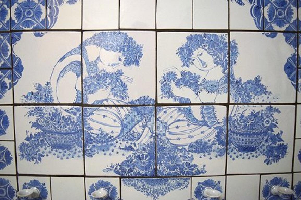 Bjørn Wiinblad (1918-2006). Huge, unique candleholder wall plaque with six light arms made of blue glazed ceramic tiles.
Hand painted with young couple and flowers surrounded by geometric ornamentation. Dated 1995.
Signed and dated.
Measures: 125