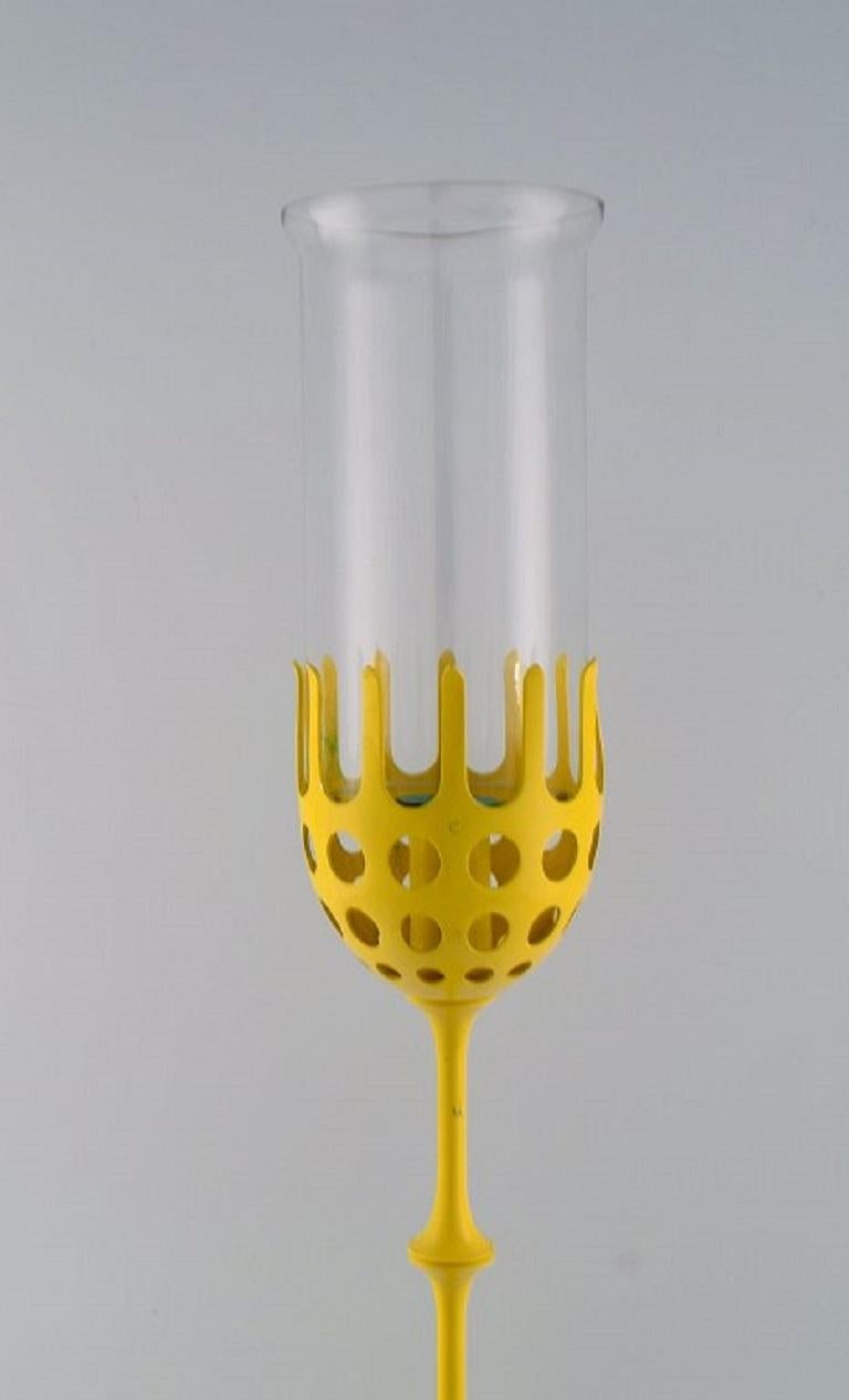 Bjørn Wiinblad (1918-2006). Large Hurricane candlestick in yellow lacquered metal with blue-tinted glass. 
1970s / 80s.
Measures: 62 x 11 cm.
In excellent condition.
A few paint peels.