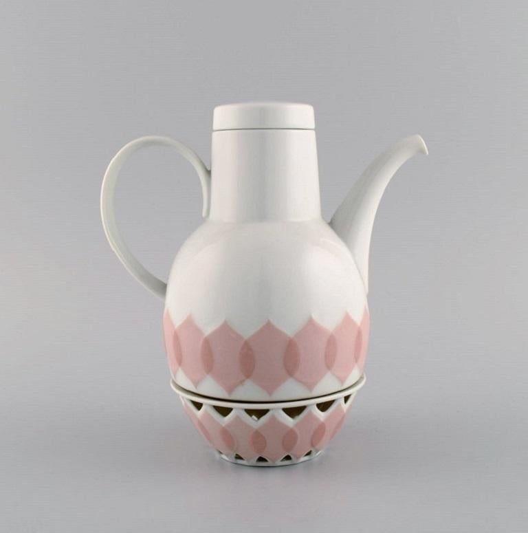 Bjørn Wiinblad para Rosenthal. Servicio de porcelana Lotus. 
Cafetera con calentador para velas candelitas y cremera decorada con hojas de loto rosa. 1980s.
La cafetera mide 21 x 18,5 cm (calentador incluido).
El cremero mide 8 x 7 cm.
En