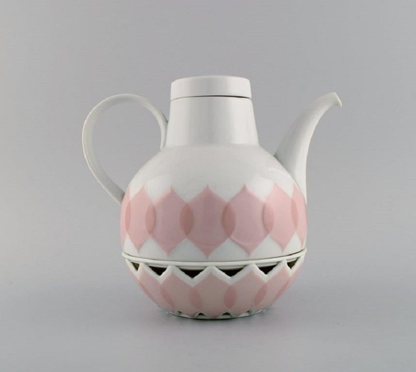 Bjørn Wiinblad für Rosenthal. Lotus-Porzellan-Service. 
Teekanne mit Heizvorrichtung für Teelichtkerzen und Milchkännchen mit rosa Lotusblättern verziert. 1980s.
Die Teekanne misst: 21 x 18,5 cm (inkl. Erhitzer).
Das Milchkännchen misst: 9 x 8