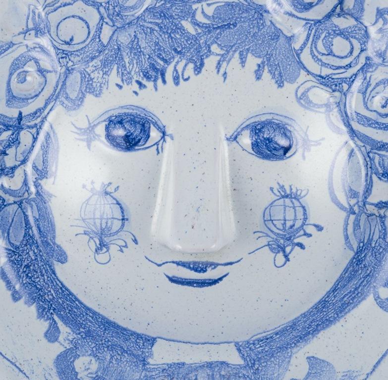 Pre-owned goods are exempt from import duties for U.S. customers. 
Therefore, no import tariffs will be applicable to your purchase.

Bjørn Wiinblad for Det Blå Hus (the Blue House). 
Unique dish in stoneware. 
Motif of a woman's face. 
Blue glaze