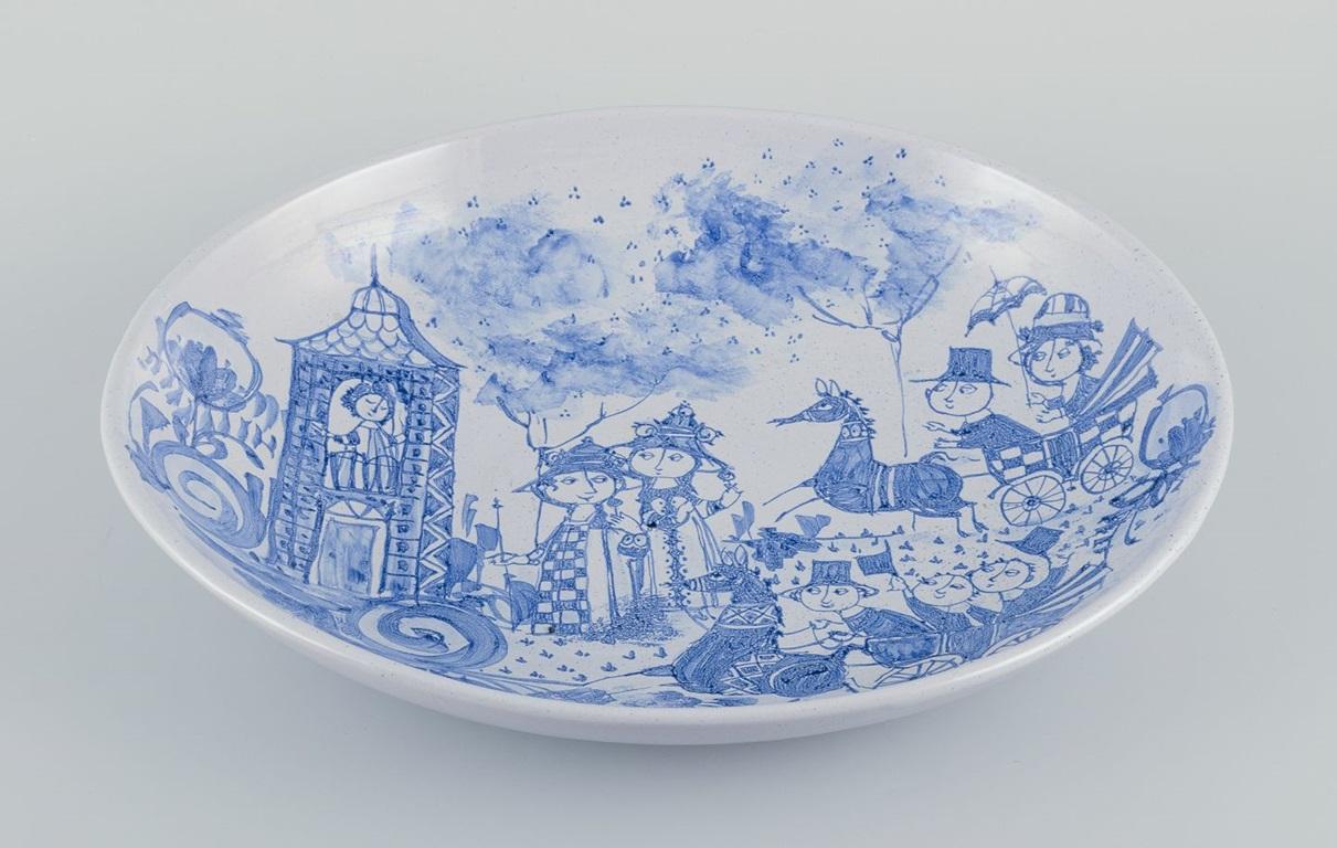 Pre-owned goods are exempt from import duties for U.S. customers. 
Therefore, no import tariffs will be applicable to your purchase.

Bjørn Wiinblad, Det Blå Hus (The Blue House), own workshop.
Large oval ceramic bowl hand-painted in blue. Motif of