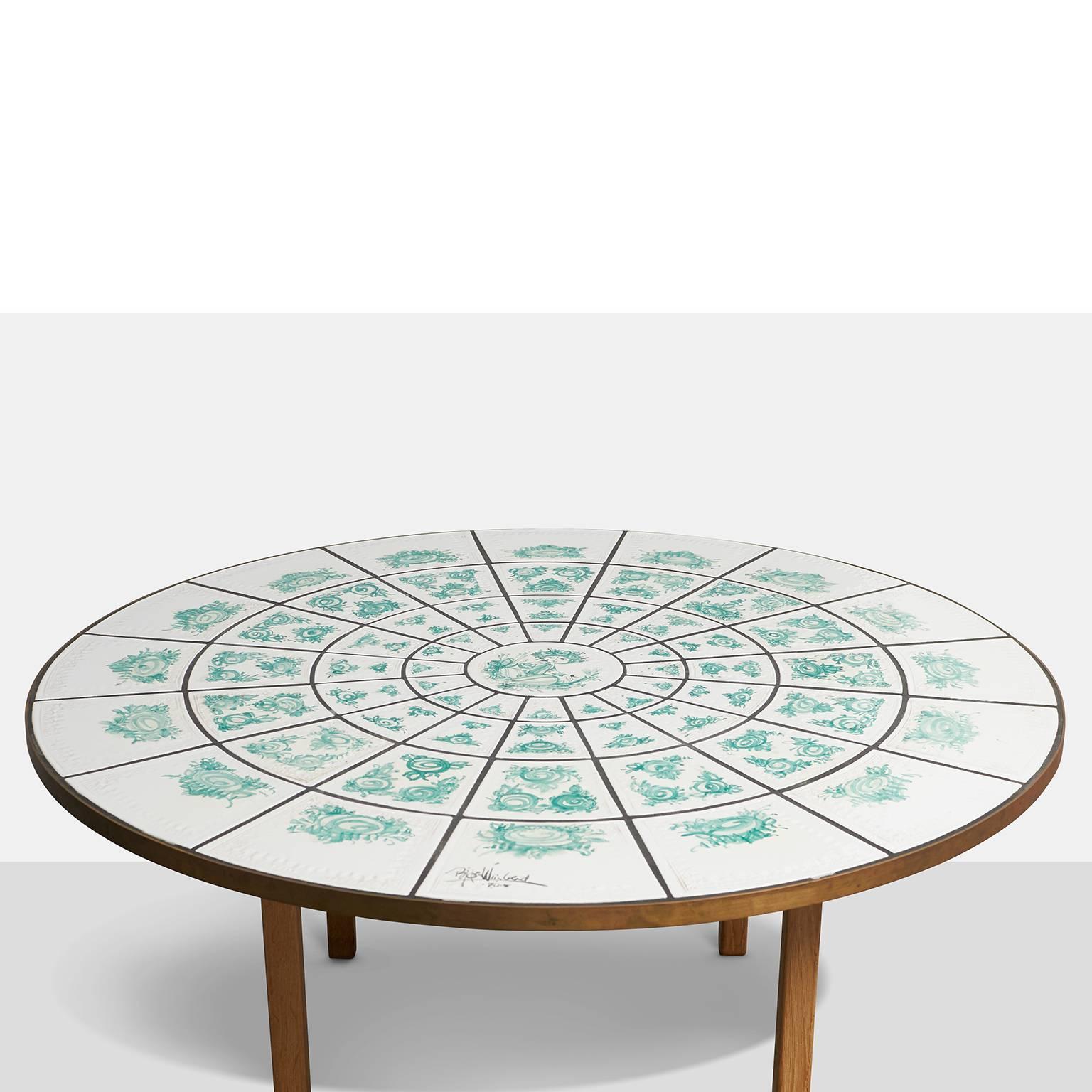 A circular coffee or center table with concentric tiles in green and white. Oak frame and legs and brass trim around the top. Signed and dated by the designer.