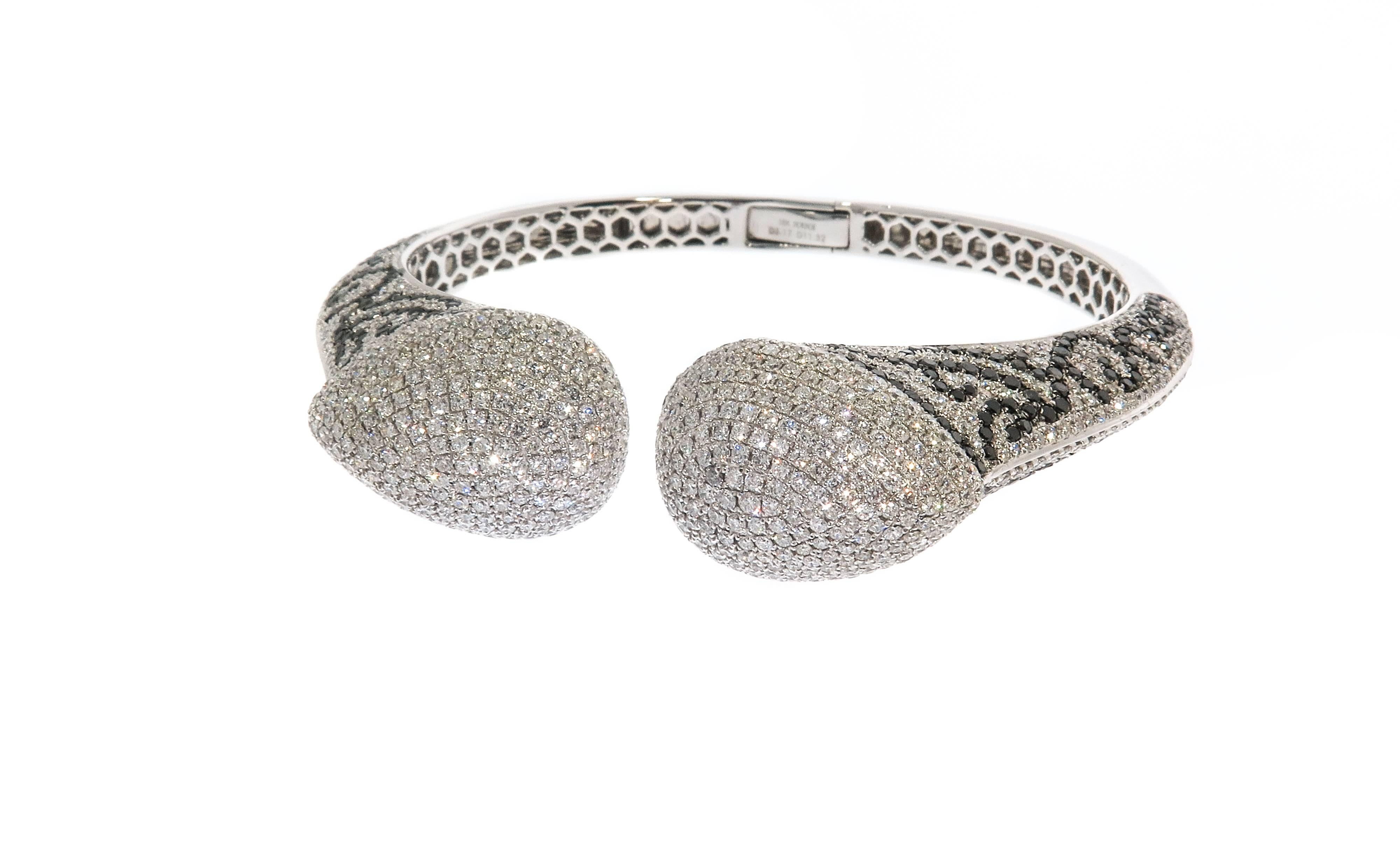 An amazing craftsmanship featured in this Diamond Cuff Bracelet, stunningly decorated with 1080 white round diamonds (11.32 carats) and swirls of 370 Black Diamonds (3.17 carats).
Handcrafted by our expert goldsmiths in 18k white gold, weighing