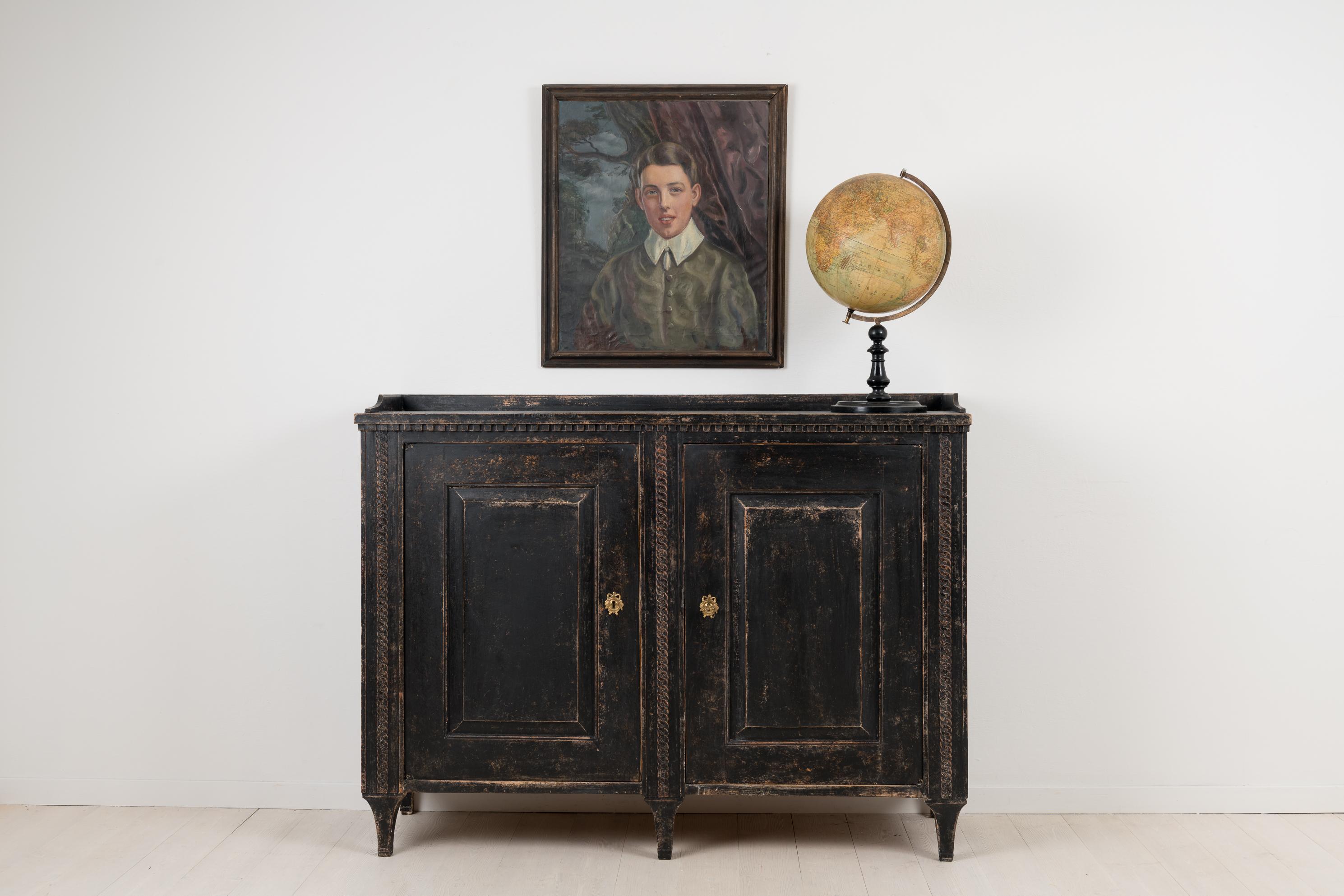 Neoclassical sideboard from northern Sweden. The sideboard is made circa 1790 from Swedish pine. It is unusually decorated with hand carved wooden decorations such as the three carved chains going vertically from top to bottom. The lock and key are