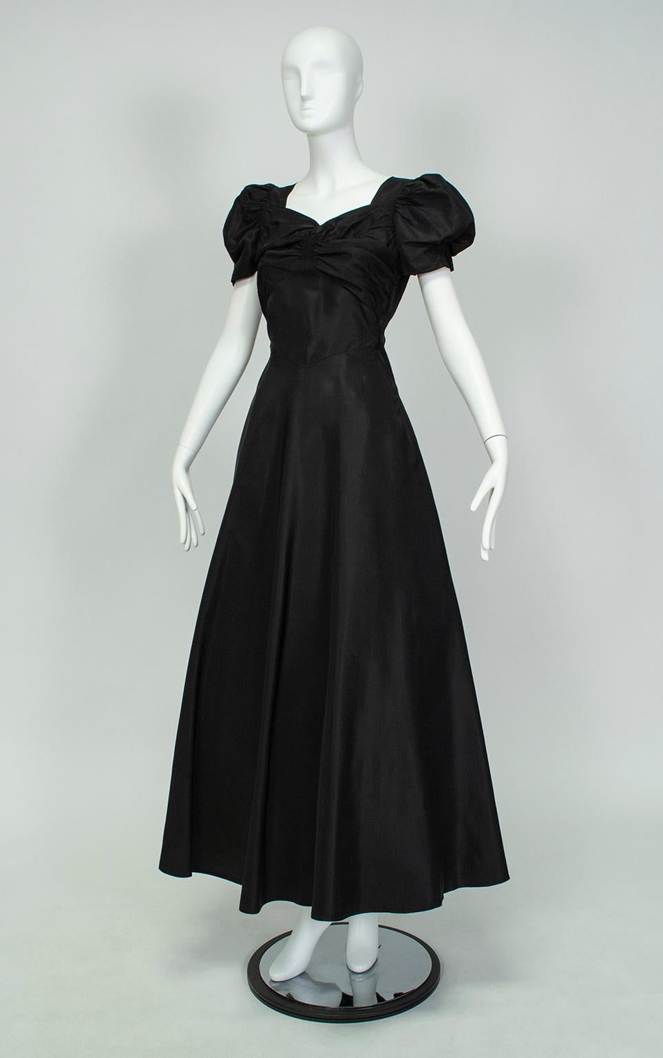 With its cascading ruffle back skirt, puffed sleeves and sweetheart neckline, this gown is like a page out of Walter Plunkett’s designs for “Gone with the Wind” or Adrian’s for “Letty Lynton”. Girlish and feminine thanks to its cut, but also serious