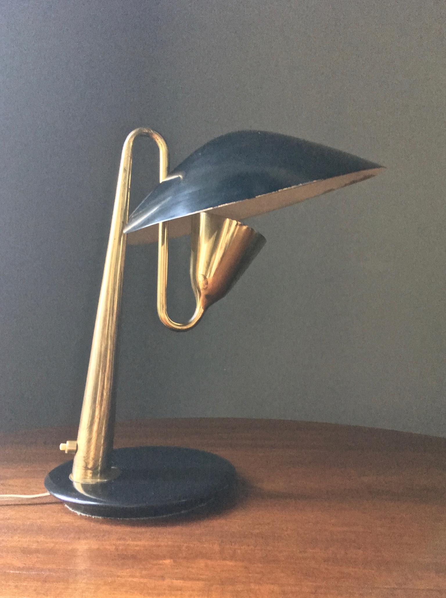 Brass table or desk lamp, with black shade and base, attributed to Giuseppe Ostuni for O-Luce (or Oluce) of Italy, 1950s.

A beautiful design, very nicely made, which allows the circular shade to be tilted through a joint at the neck. The lamp is