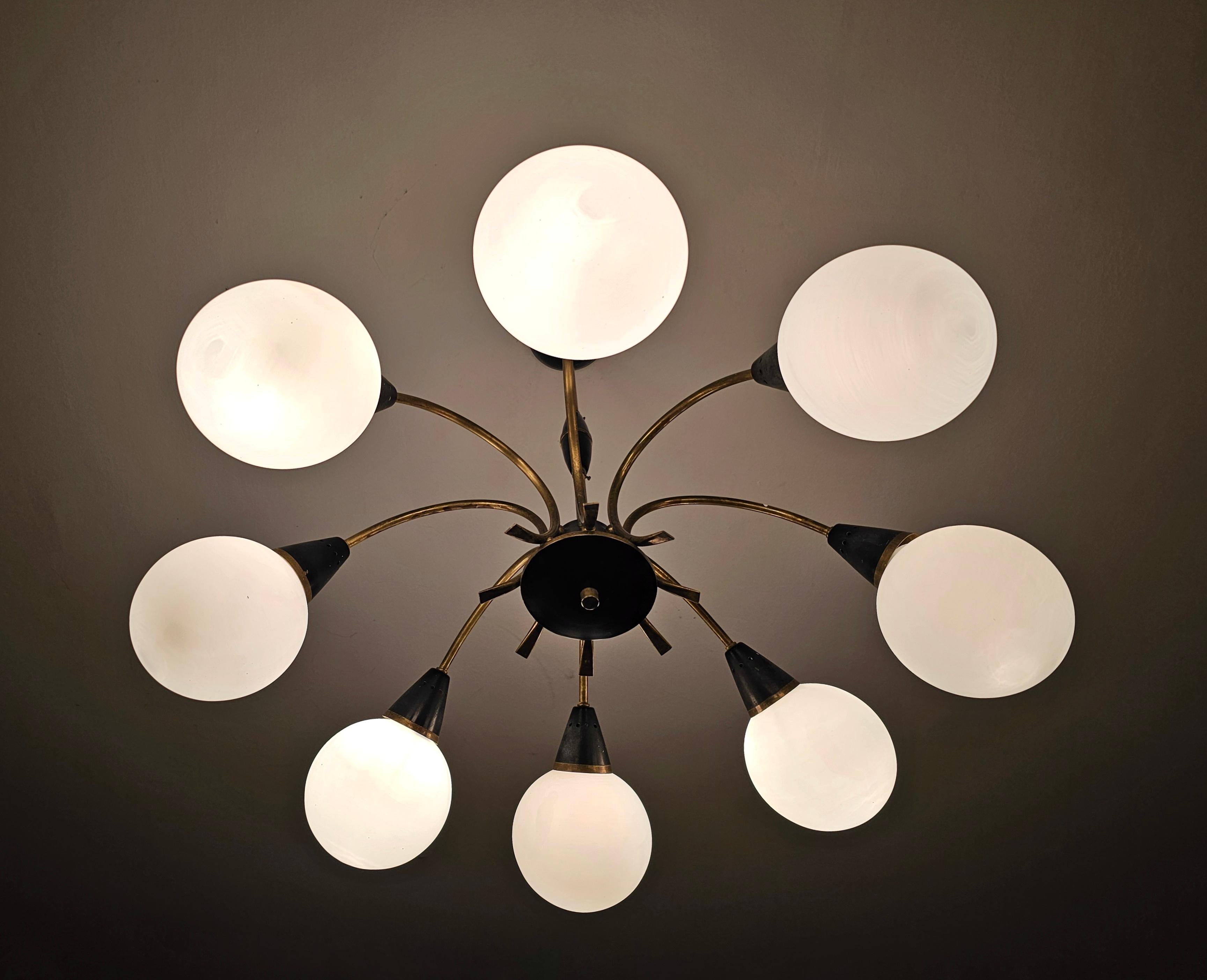 In this listing you will find a stunning 8-Arm Mid Century Modern Chandelier attr. to Stilnovo. It is done in brass and black painted brass, with 8 lights within opaline glass balls and spider-like shape. Made in Italy in 1950s.

Good vintage