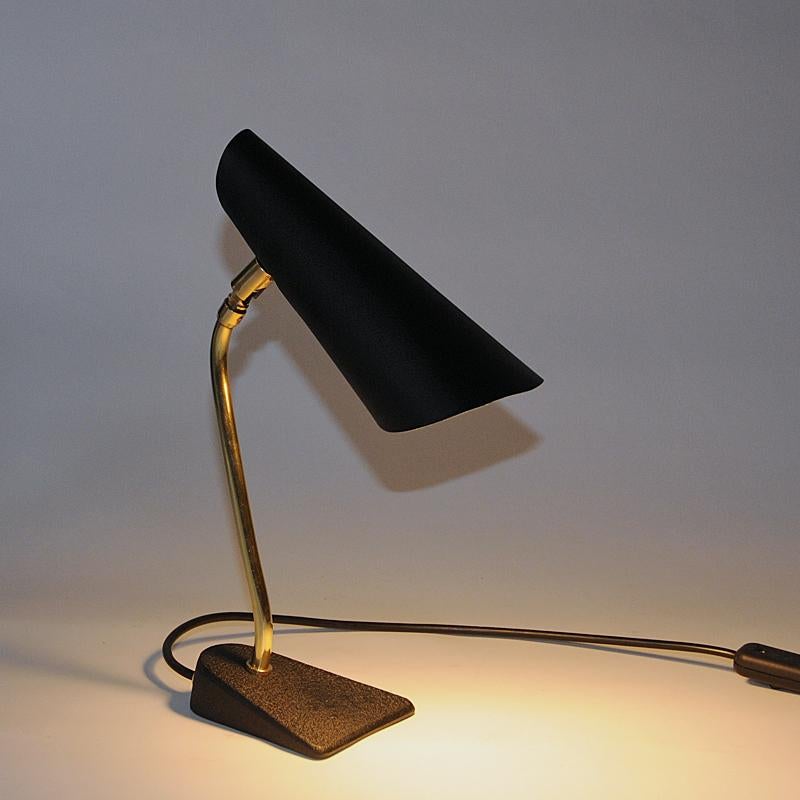 Classic and elegant black metal desk or/and tablelamp with adjustable head in all directions. Good vintage design. Beautiful coneshaped head on a brass stom and a black iron base. White colored inner shade. Perfect vintage condition. Light switch on