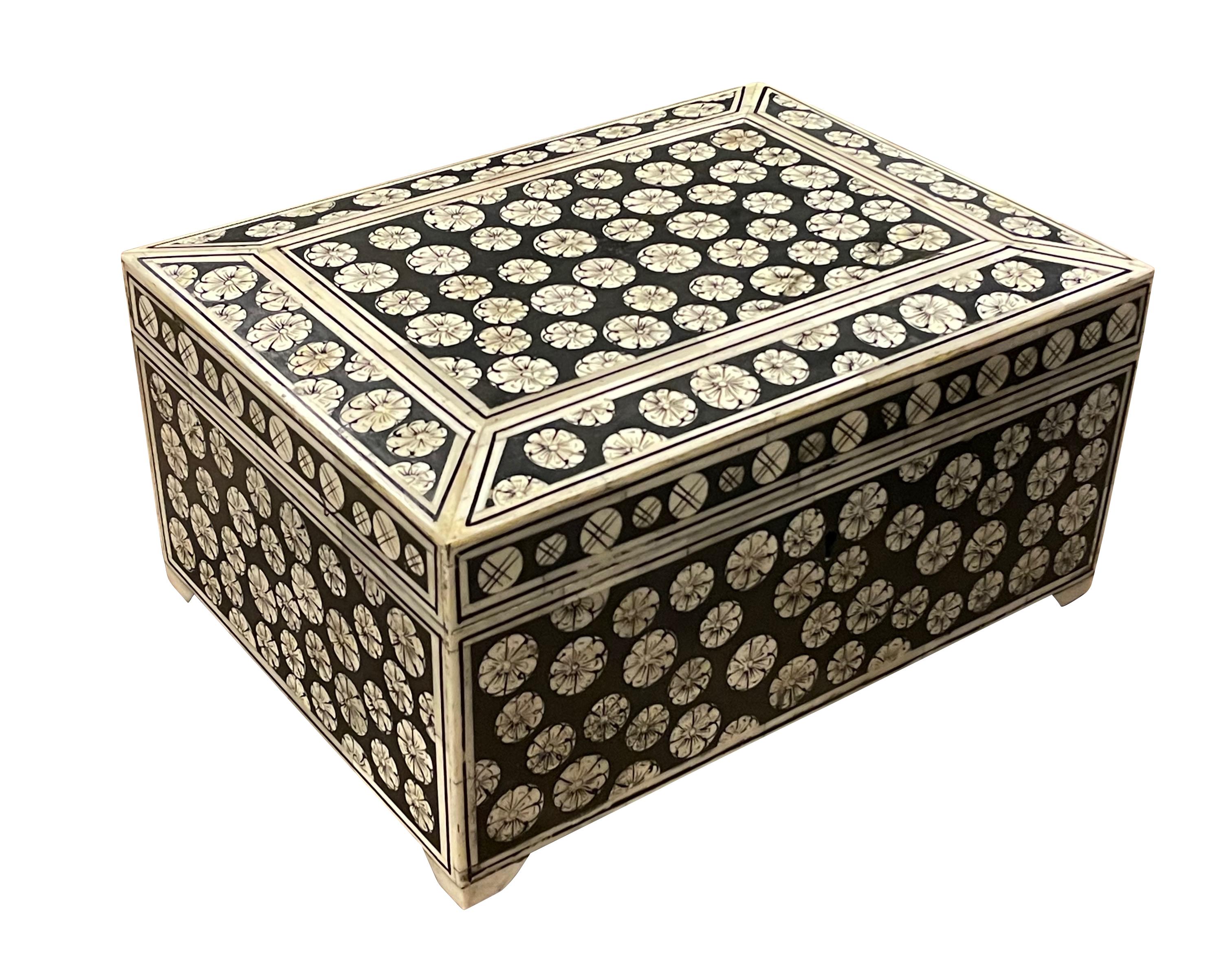 Caja india contemporánea de hueso con fondo negro y diseño general de círculos decorativos de color crema.
Parte superior ligeramente elevada en forma de pirámide.