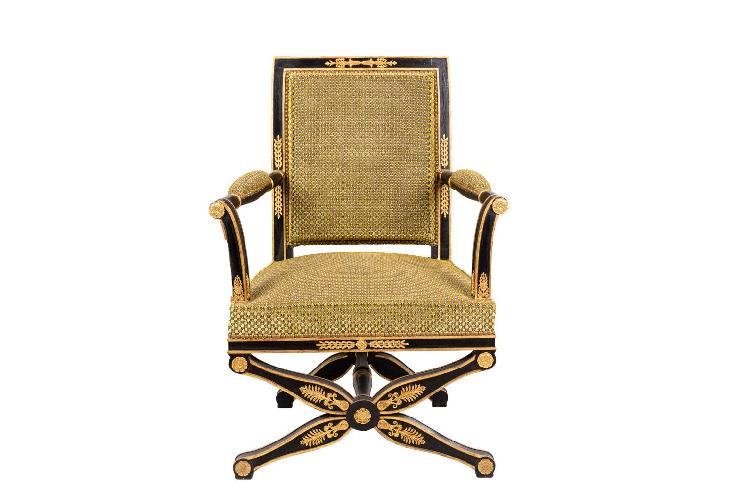 Fauteuil de style Empire en bois laqué noir sur un pied en forme de X, habituel sur les chaises Curule de ce style. Dossier et montants droits, sauf console d'accoudoir légèrement inversée. Les rehauts dorés présentent des motifs de style Empire