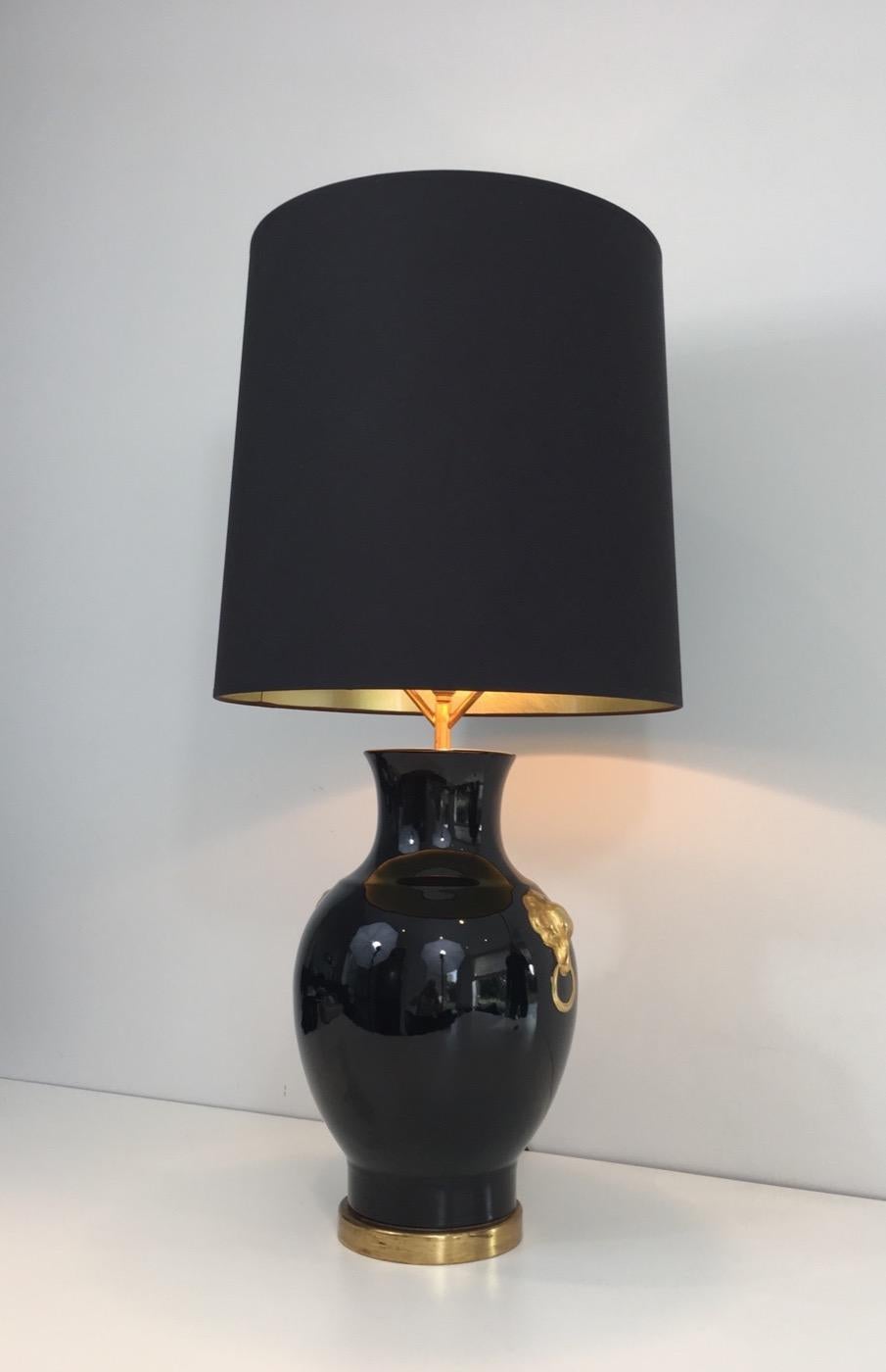 This table lamp is made of a black ceramic with gold decorations on each side. It stands on a gold base. The balck shintz shade gold inside is new. This is a very decorative lamp. This is a French work, circa 1970.