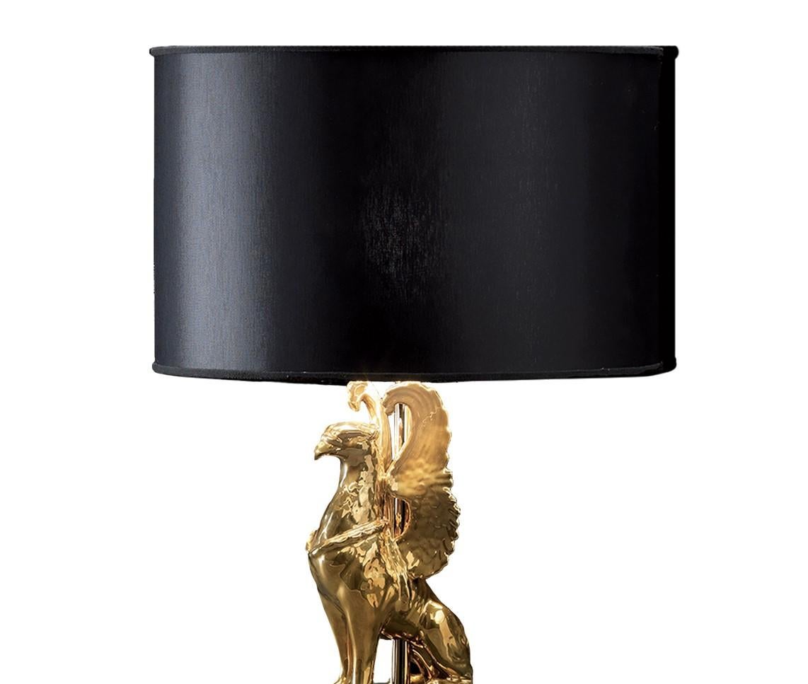 This lamp, entirely crafted in ceramics, will add a touch of grandeur to any home. It's black square-shaped base acts as a pedestal supporting on its top a perfect rendering of a dignified griffon sitting at attention. The griffon has been covered