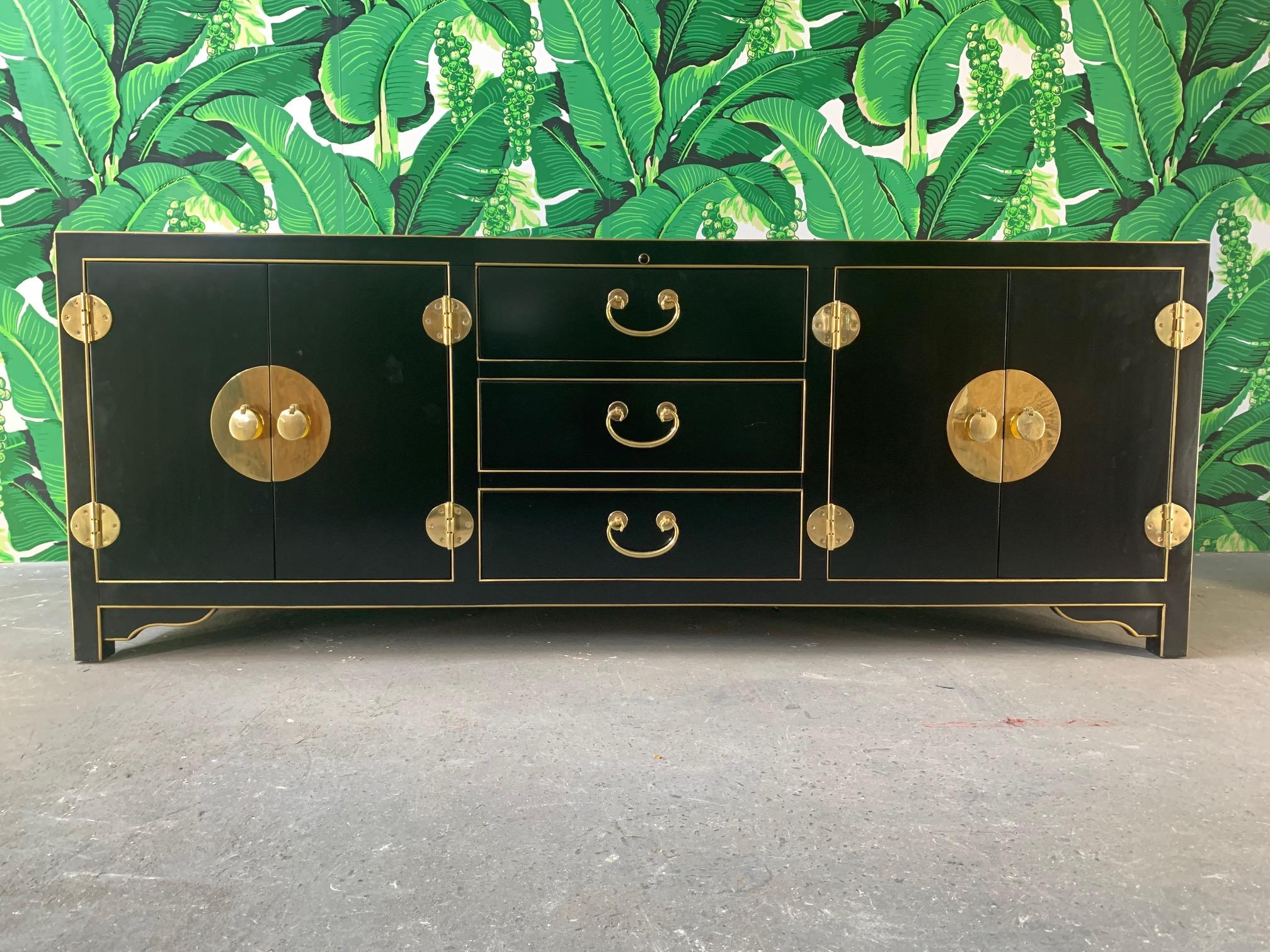 Credenza by Sligh Furniture features brilliant black finish with gold detailing and heavy brass hardware. Three drawers and two double door sections revealing shelving for storage. Includes infrared SmartEye for media remote control. Very good
