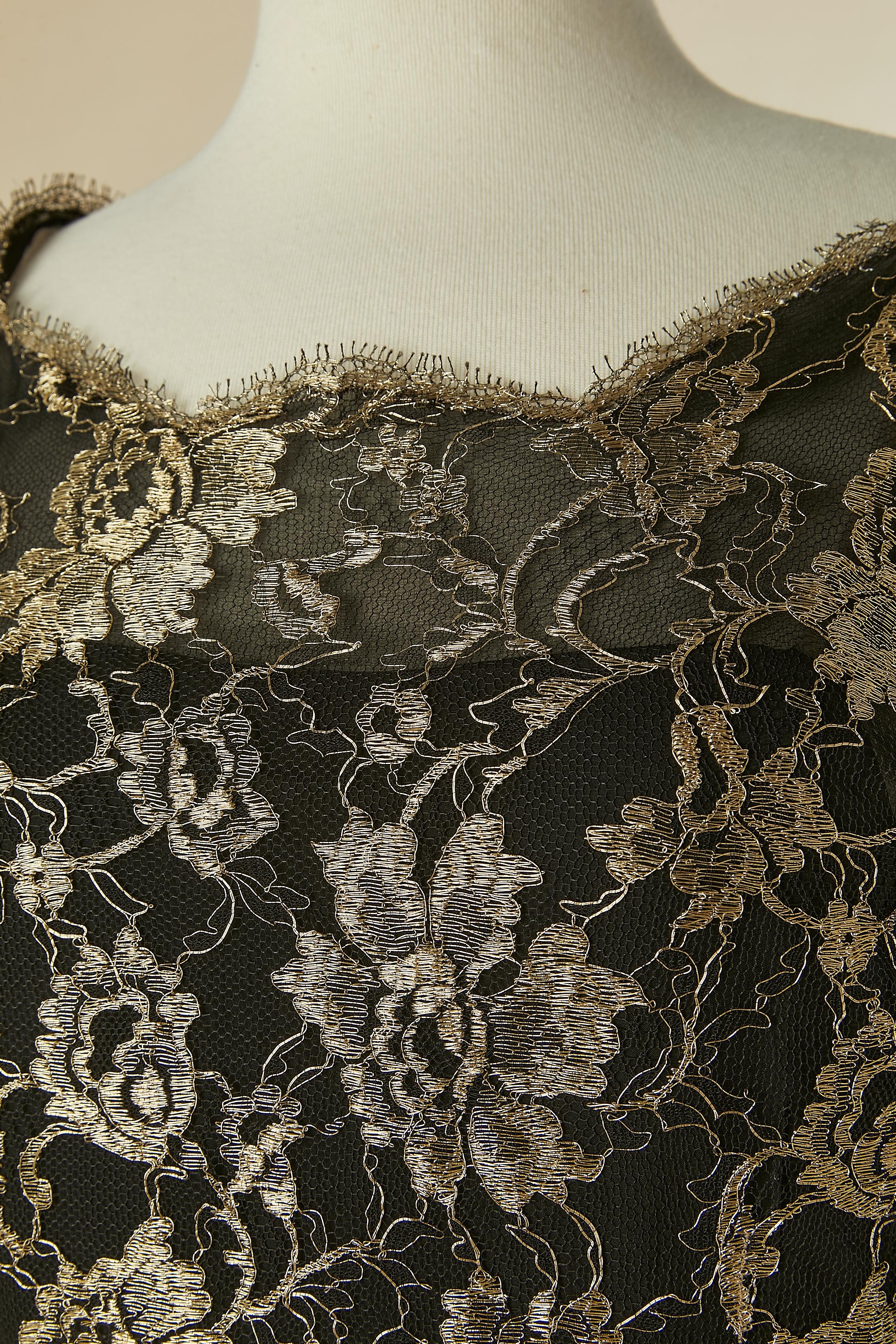 Schwarz-goldenes Spitzenabendkleid mit Schleppe. Zusammensetzung der Spitze: 20% Nylon, 80% Polyester. Schwarzes Seidenfutter. 
Mit Spitze überzogener Knopf und Knopflochverschluss in der hinteren Mitte. Reißverschluss in der hinteren Mitte des
