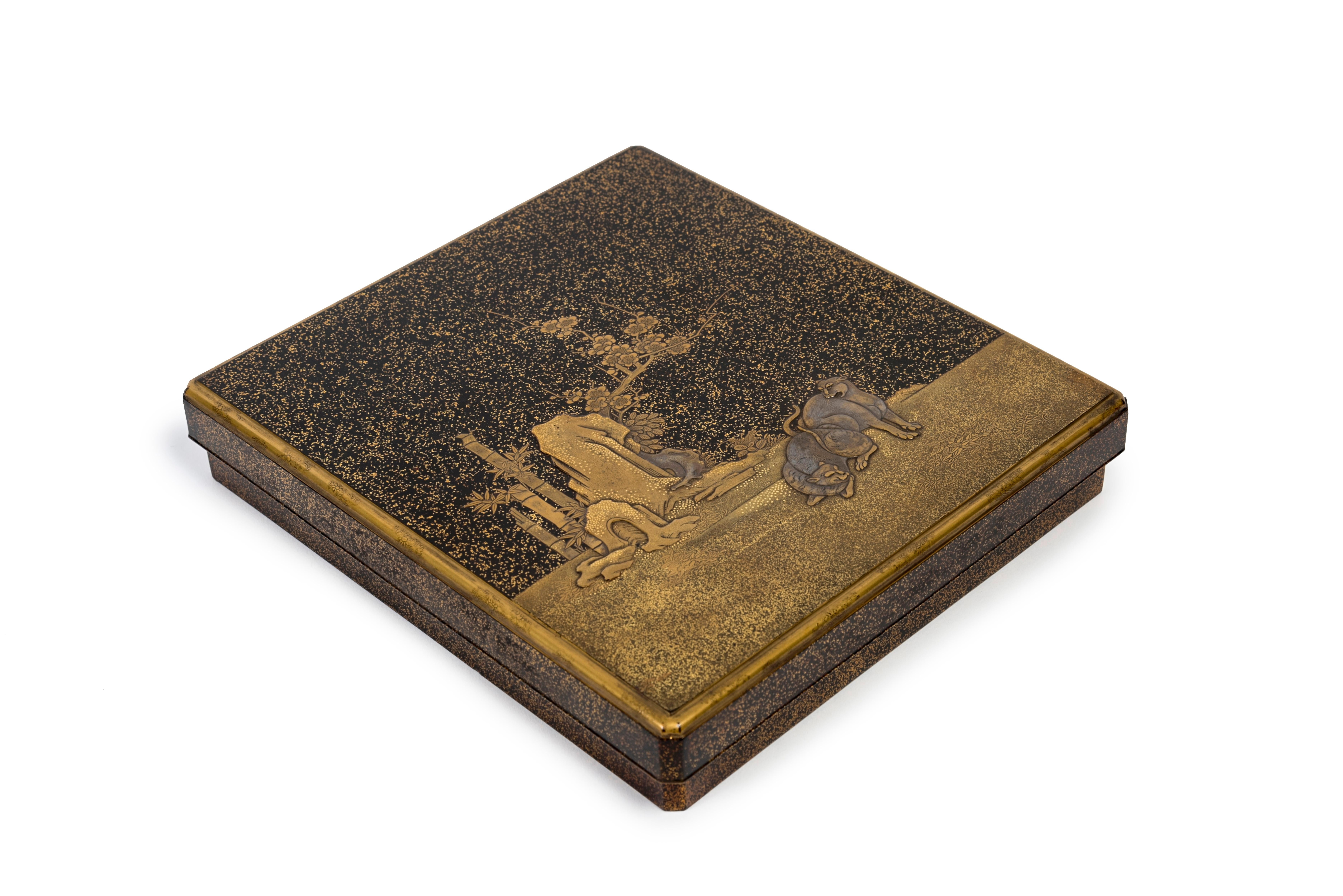 Black and gold lacquer suzuribako (writing set) in takamaki-e on a nashi-ji background representing two tigers near rocks, bamboos and plum blossoms in a night landscape. Inside of the lid with a lake landscape.
The interior of the suzuribako is