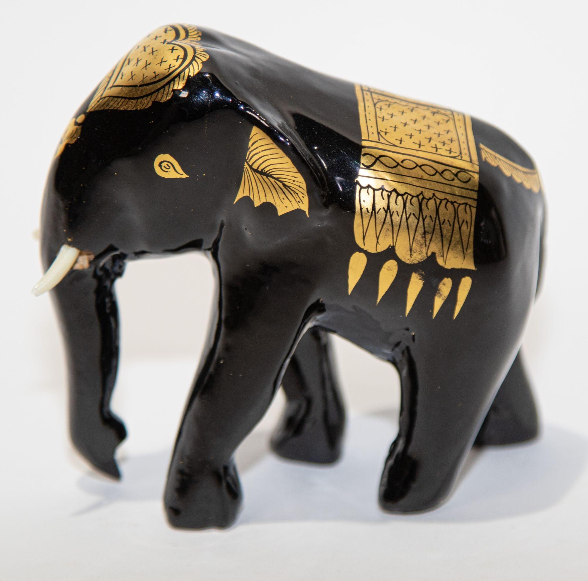Black and Gold Lacquered Thai Elephant sculpture.
This small elephant sculpture was handcrafted and hand-painted with several coats of glossy black lacquer and than the ceremonial attire is finely hand painted with 24 karat gold foil, trunk