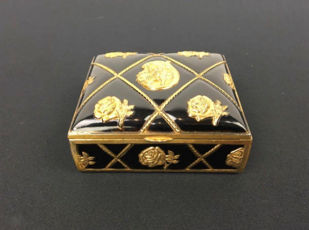 Black and gold box with roses. 
A stylish little box which can be used as jewelry box or trinket box or make-up box. Box has black color with embossed gold roses and lines in the shape of cords. Inside this little storage box with lid is there is
