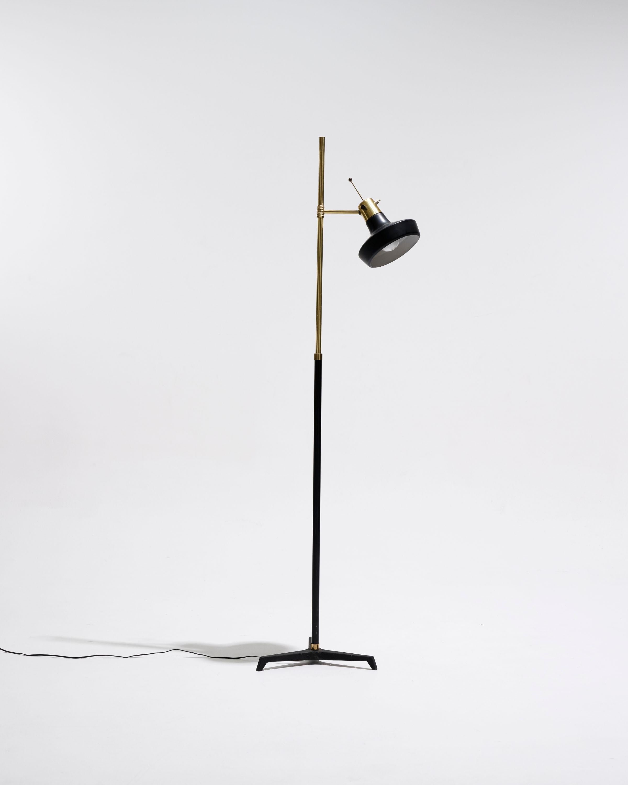 Modernist floor lamp from the 1950s. It features a black and gold tubular structure. The cross-shaped base rests on a black and gold lacquered metal frame. The adjustable spotlight allows for directional lighting. Fitted with functional wiring and a