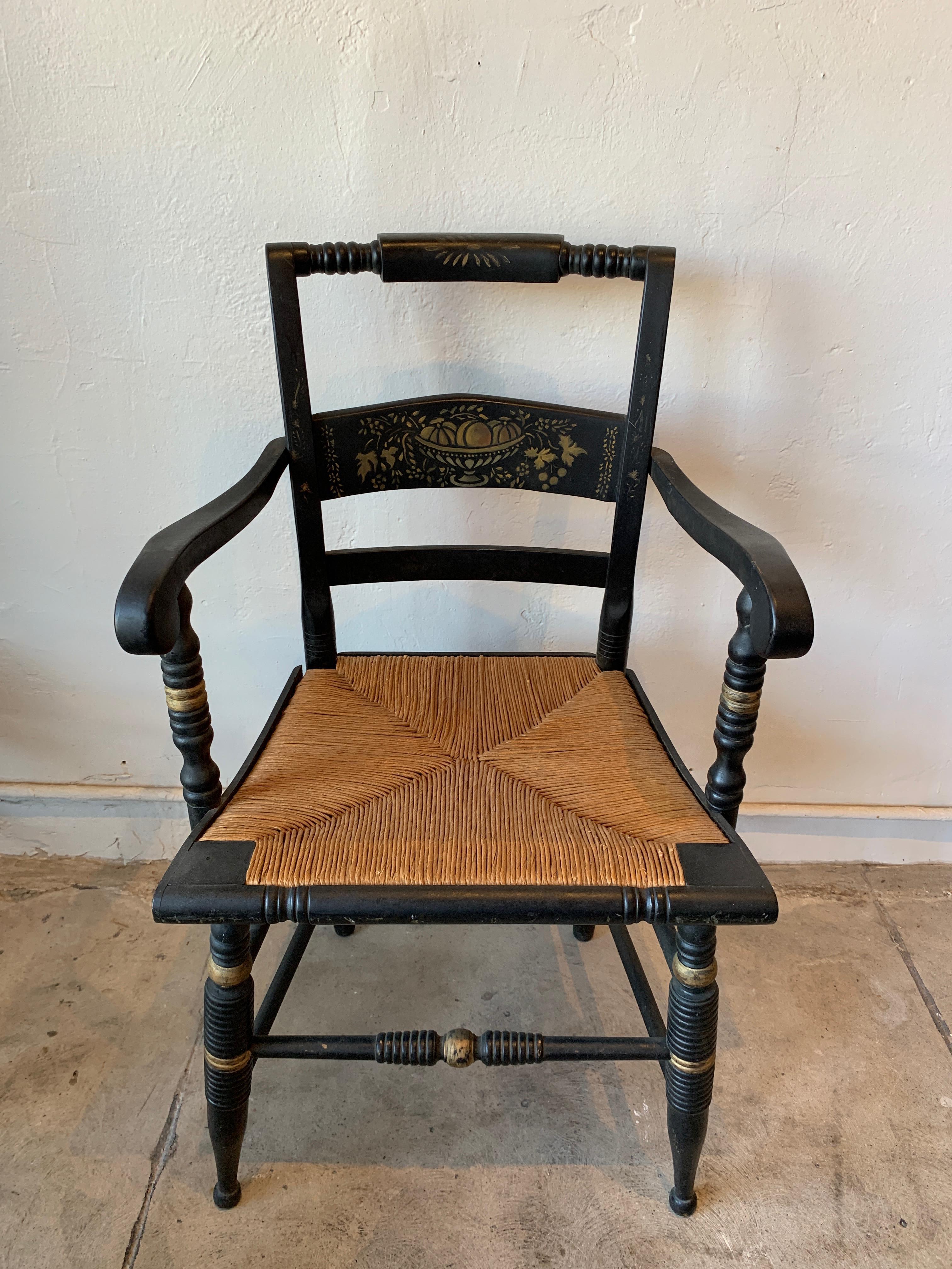 Set of five Hitchcock chairs, one armchair. Each chair has it's original rattan seat and is painted with gold motifs. A beautiful dining set with the armchair at the head of the table.