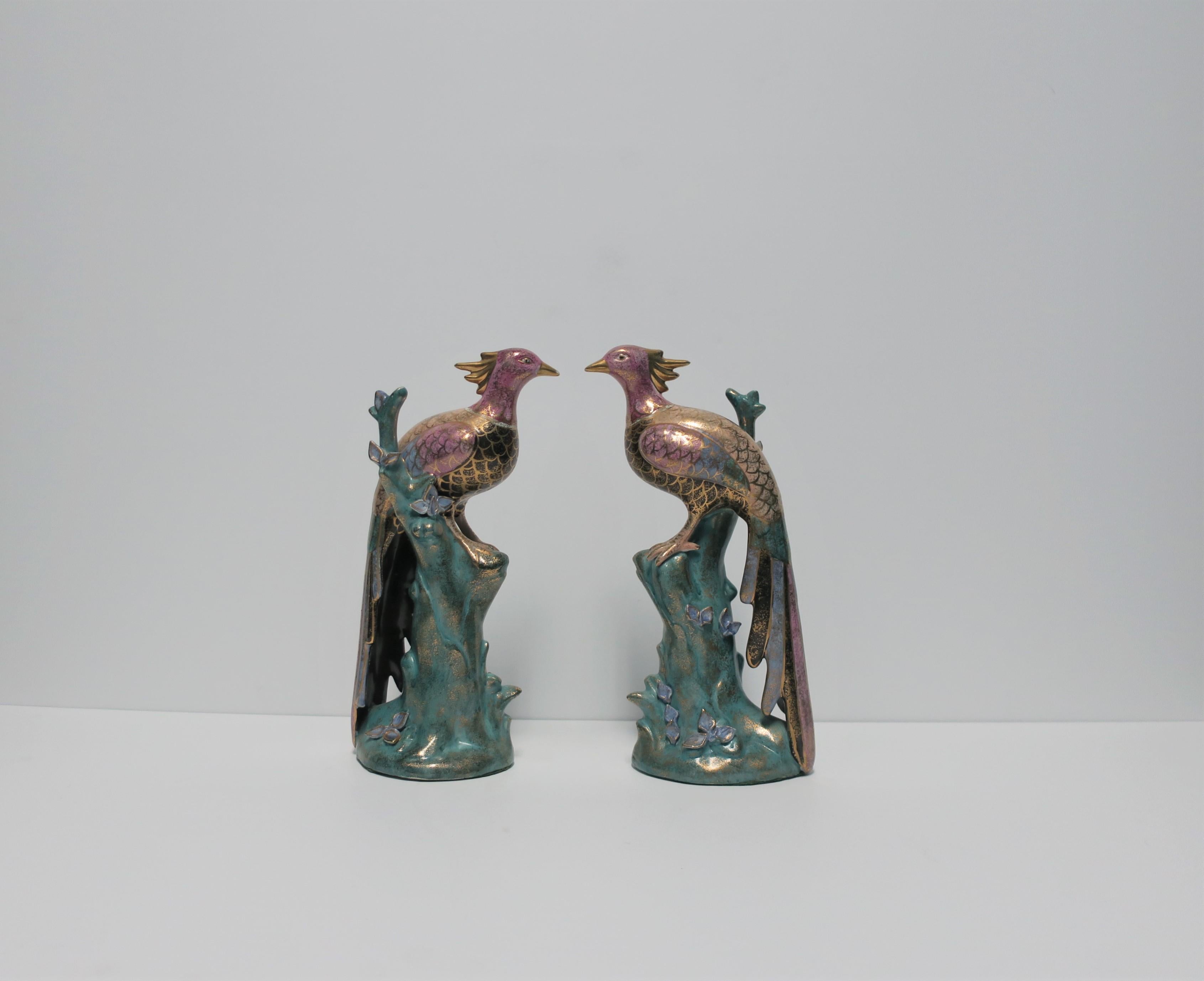 A beautiful and detailed pair of mid-20th century or earlier black and gold peacock or phoenix bird ceramic sculptures decorative objects perched on branch. Each peacock or phoenix bird is relatively tall measuring 10.5