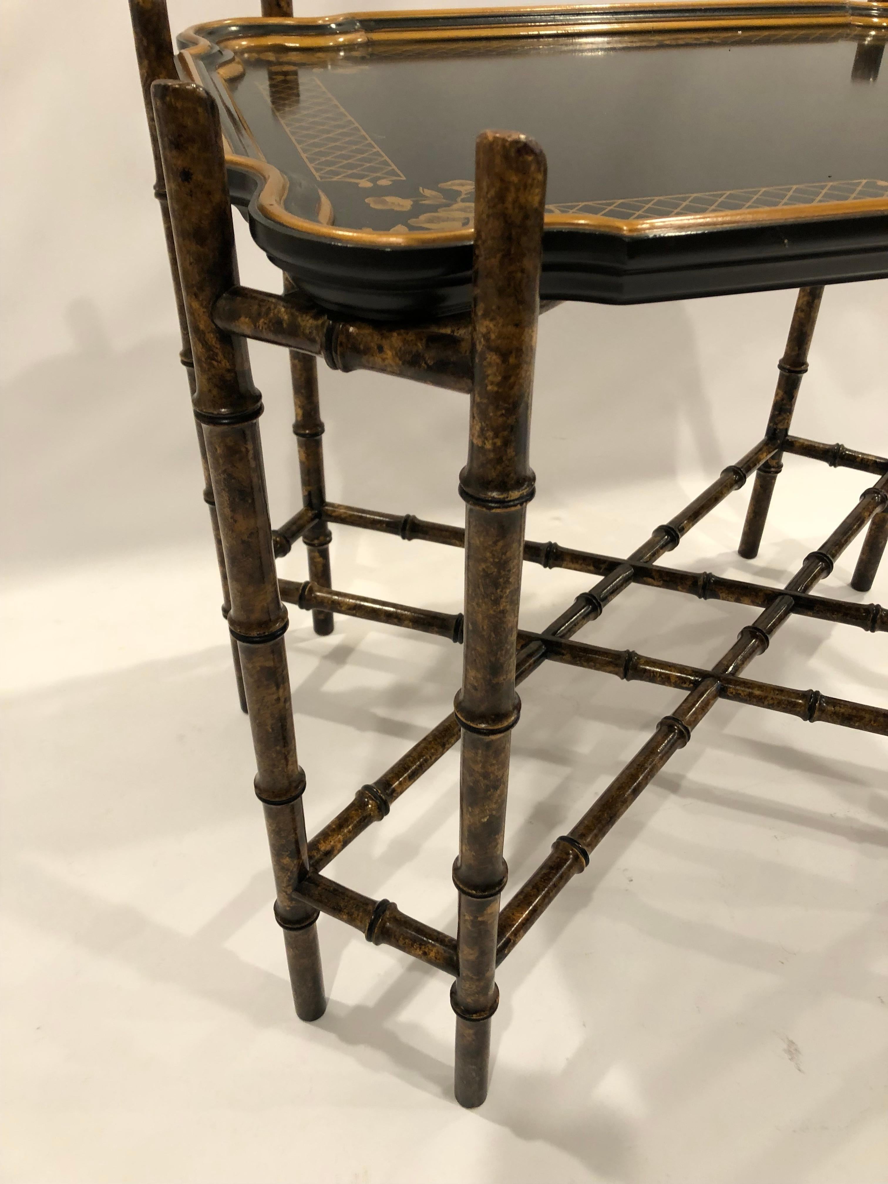Élégante table basse à plateau d'inspiration Regency, noire et dorée, avec une base en forme de bambou et un plateau amovible festonné et décoré sur le pourtour.