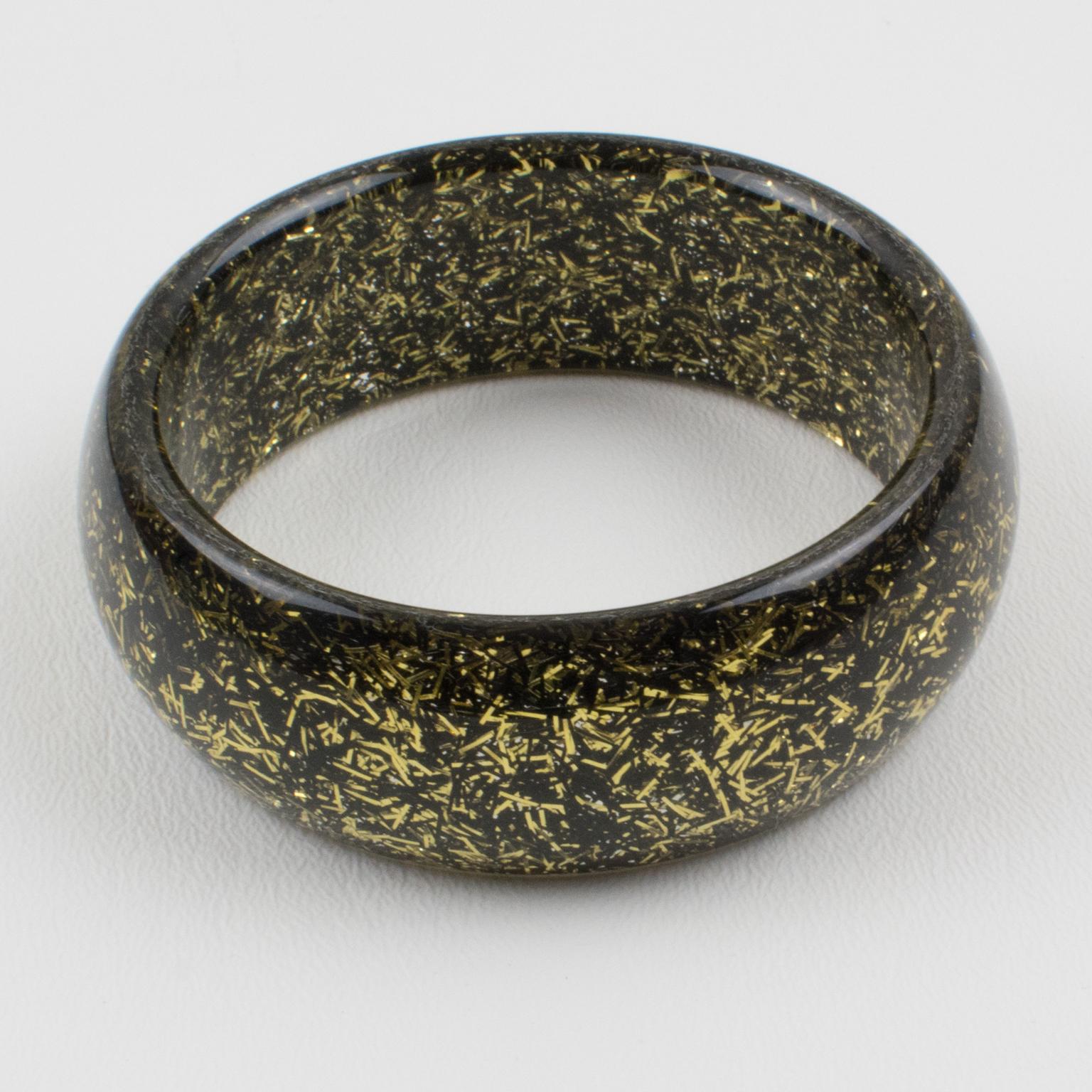 This lovely lucite bracelet bangle has a domed shape and comprises clear lucite injected with metallic thread inclusions in black and gold. The metallic threads sparkle like Christmas tinsel. There is no visible maker's mark.
Measurements: Inside