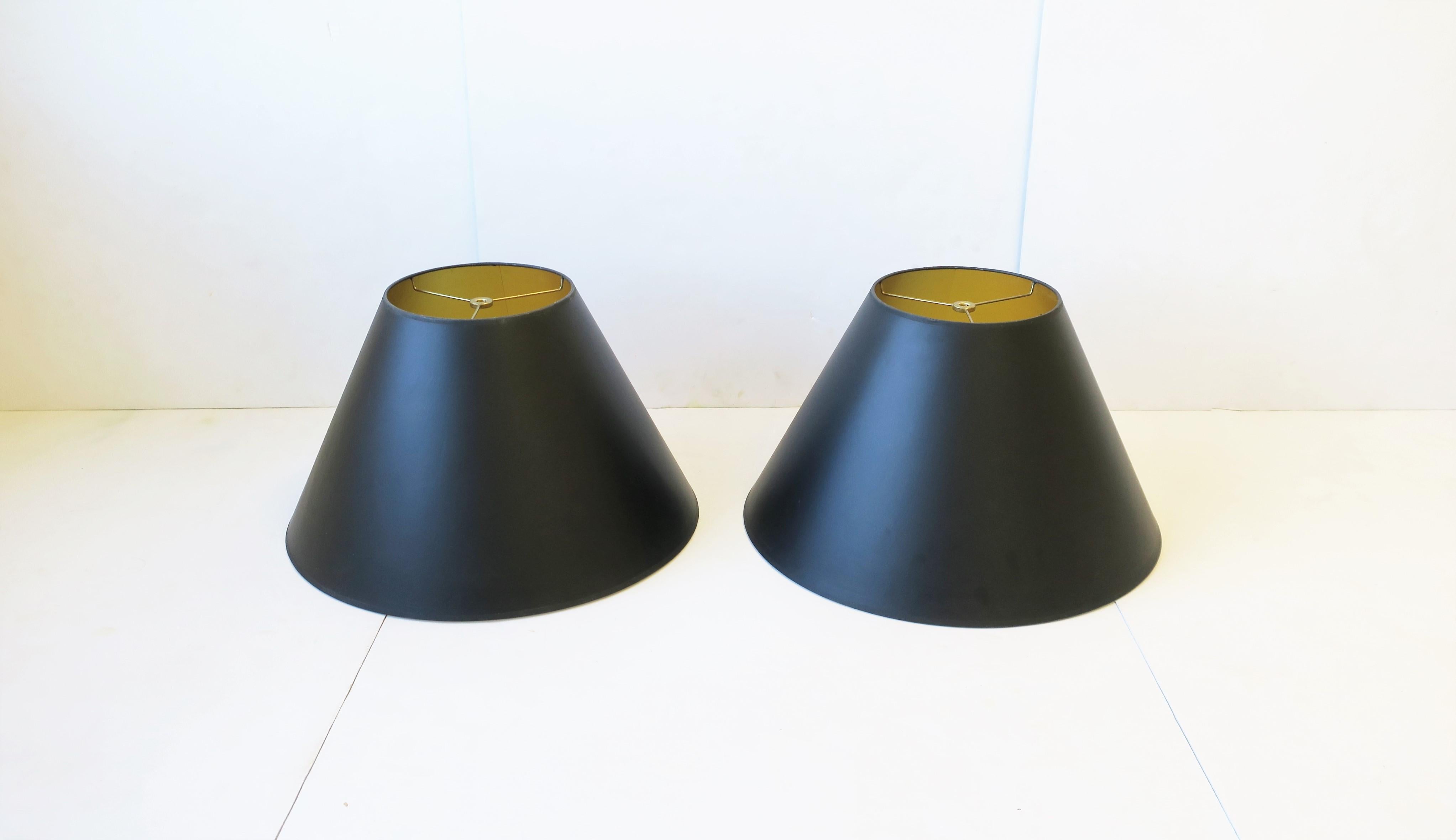 A pair of black paper lampshades [lamp shades] with gold interior and brass hardware. Dimensions: 19