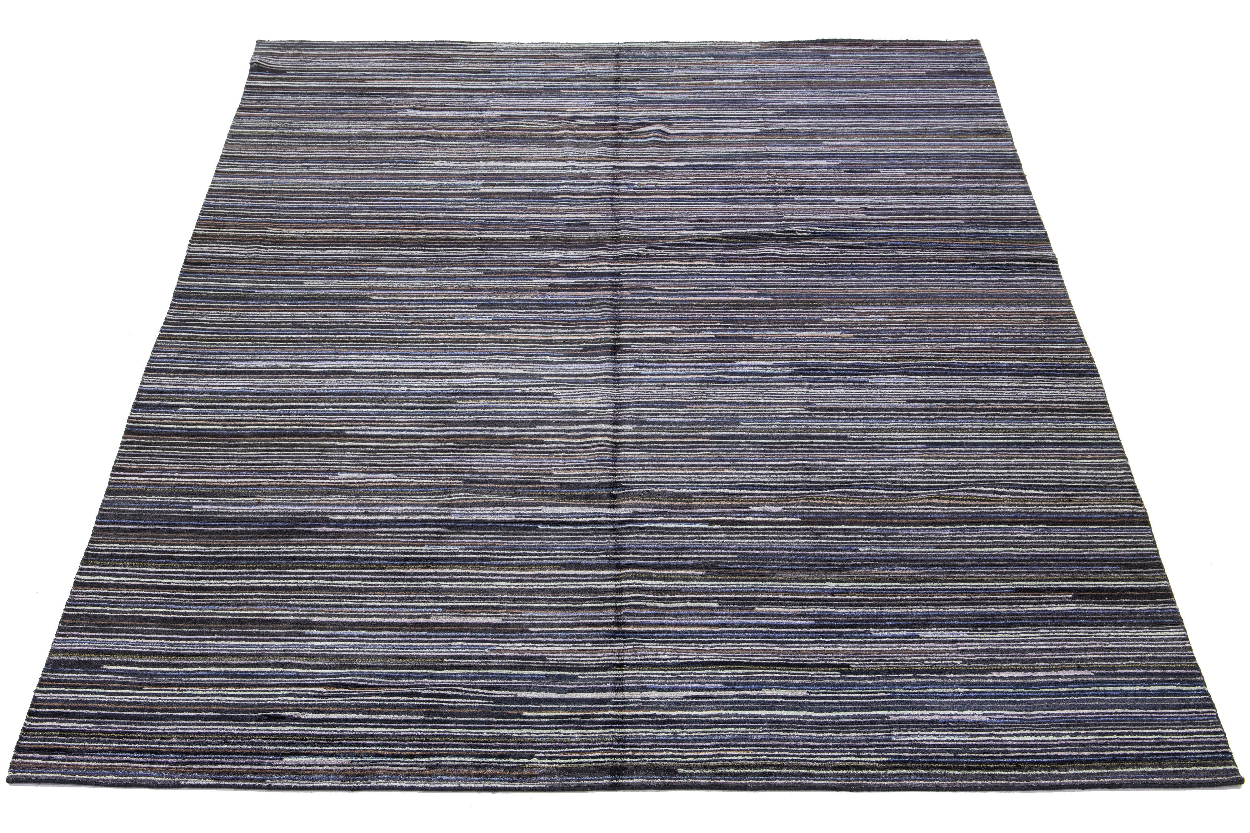 Dieser handgeknüpfte indische Teppich besteht aus Wolle und besticht durch seine Streifenästhetik mit mehrfarbigen Akzenten. Der Hintergrund ist in natürlichen Grau- und Schwarztönen gehalten.

Dieser Teppich misst 10' x 14'4