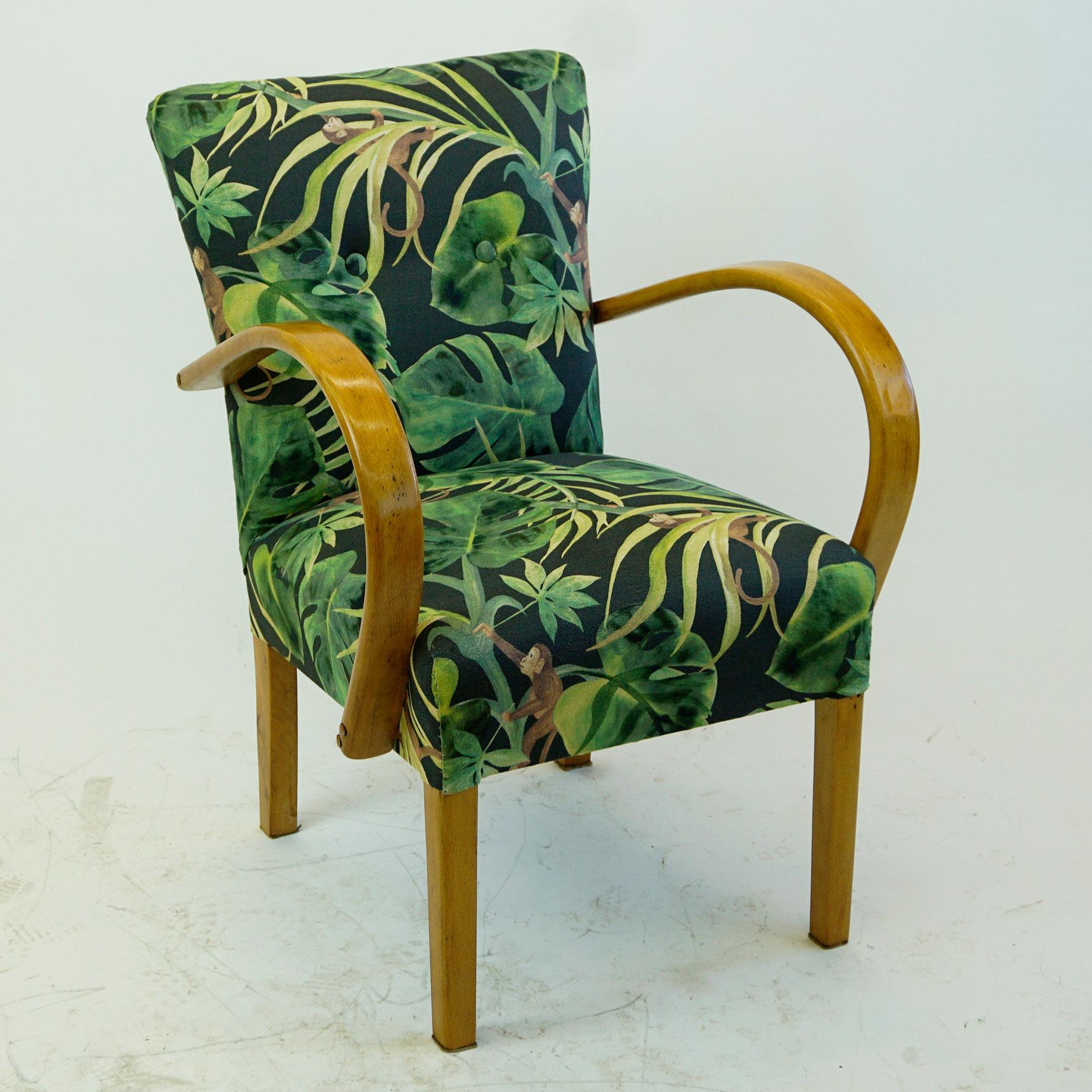 This charming Art Deco armchair has been completely restored and newly upholstered. The structure in beechwood features striking armrests that were curved using steam. The new upholstery is in black and green fabric with floral motifs and apes.
