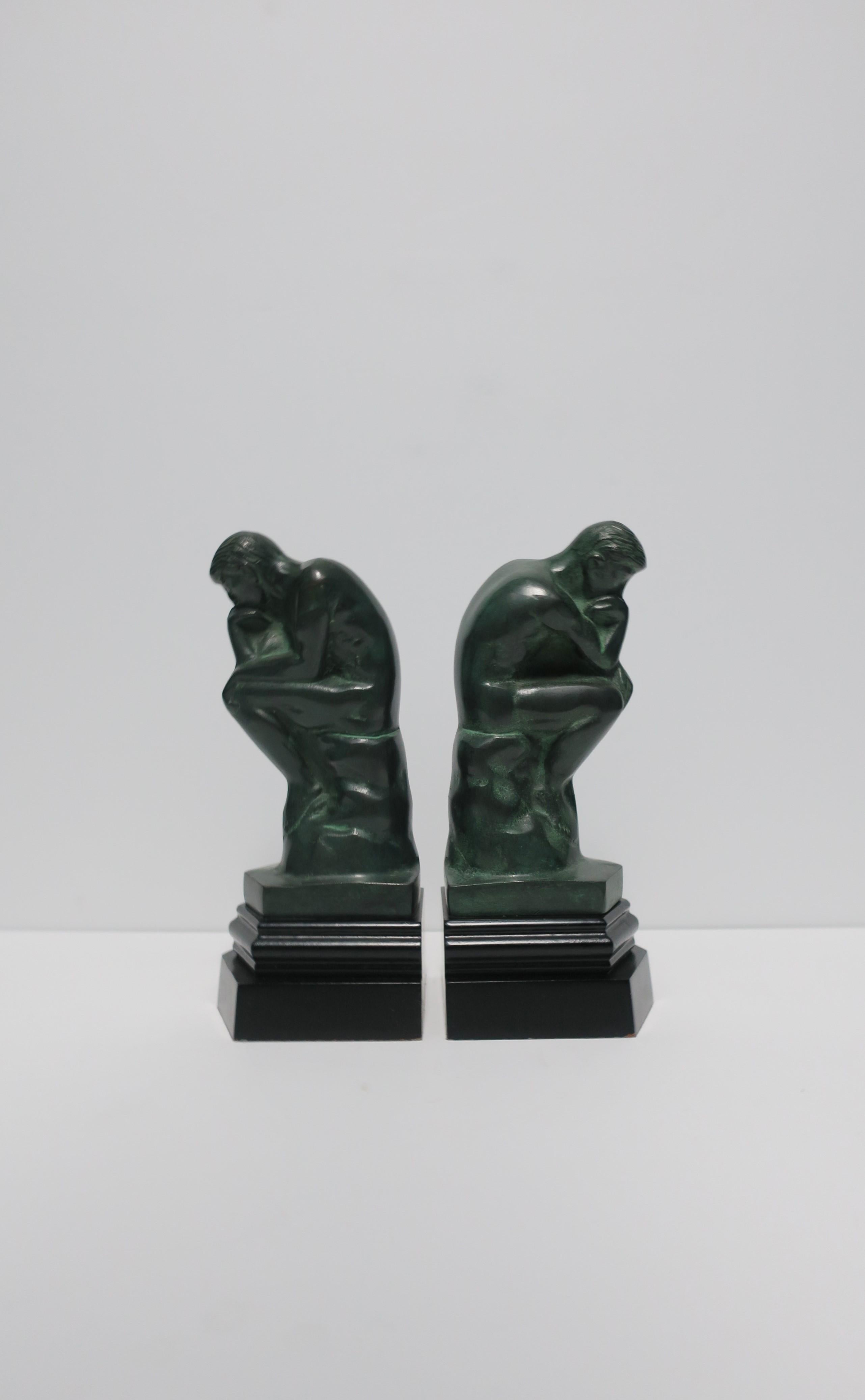 A great pair of 'Thinker' male figurative sculpture bookends in dark green with black bases, circa late 20th century. Each measuring 9.25