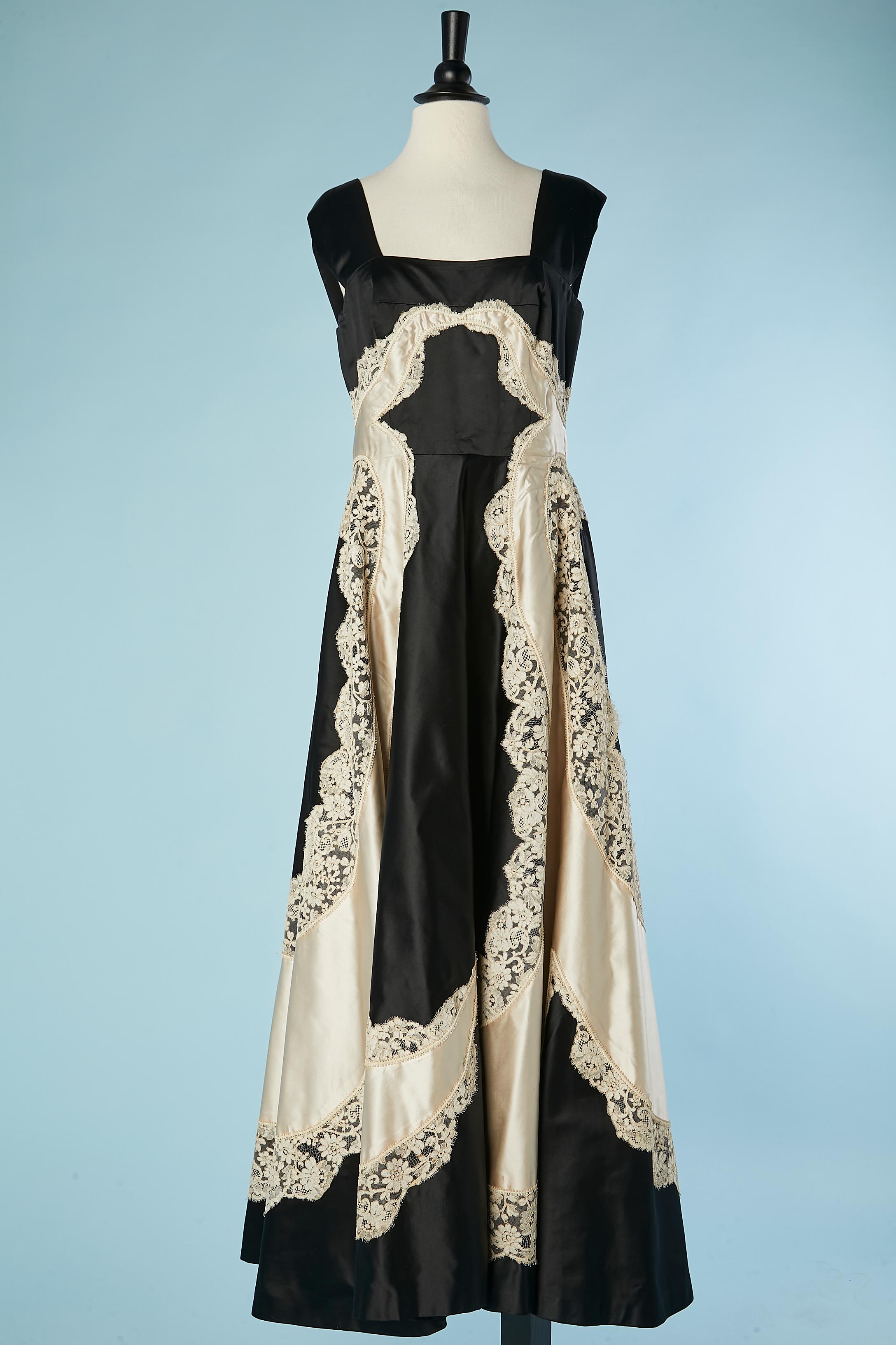 Black and ivory satin evening dress with lace appliqué. Boned. Zip and hook and eye in the middle back. Stiff paper/fabric lining. 
SIZE L