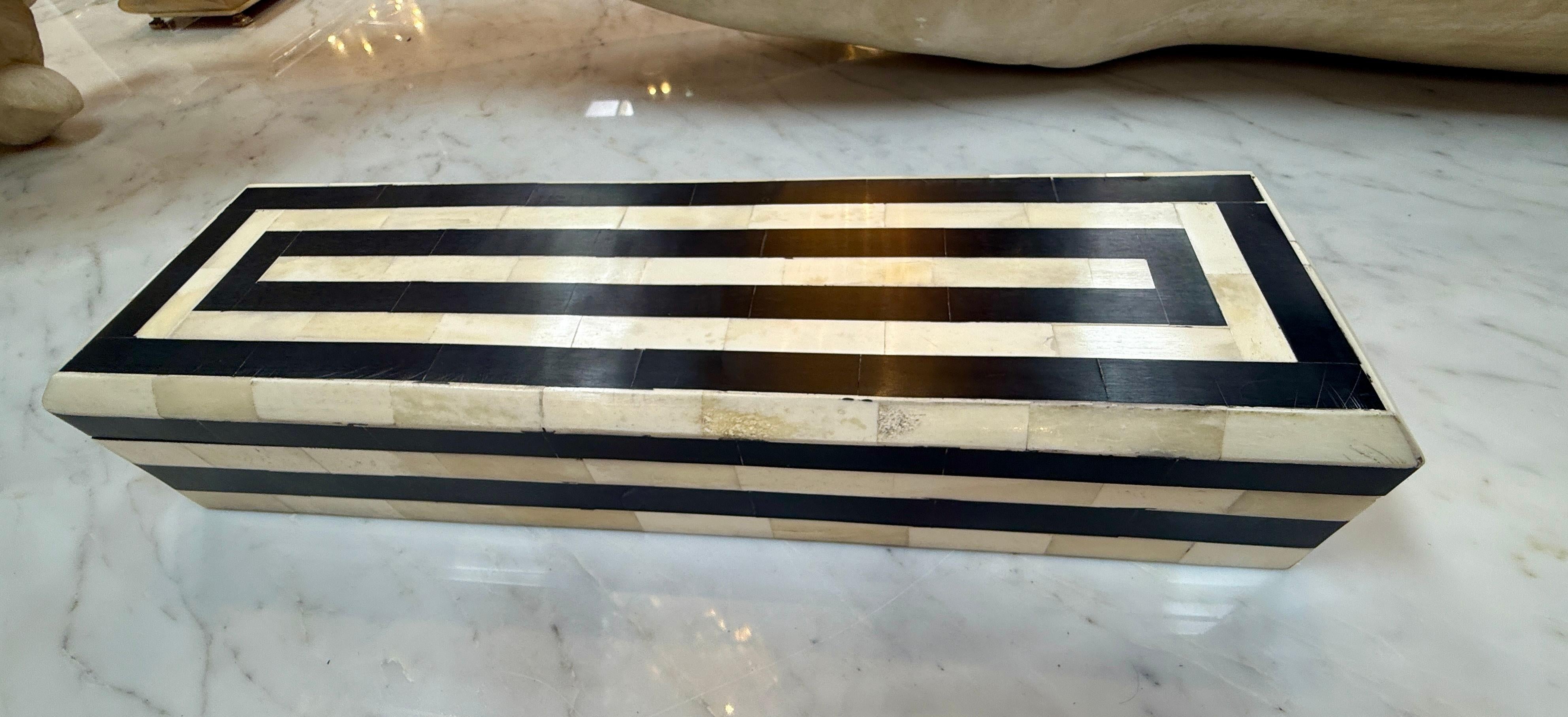 A sleek and elegant rectangular box, this piece is crafted with a striking black and ivory bone inlay in a bold geometric pattern. Its elongated form makes it perfect for holding jewelry, keepsakes, or desk accessories, while the crisp contrast of